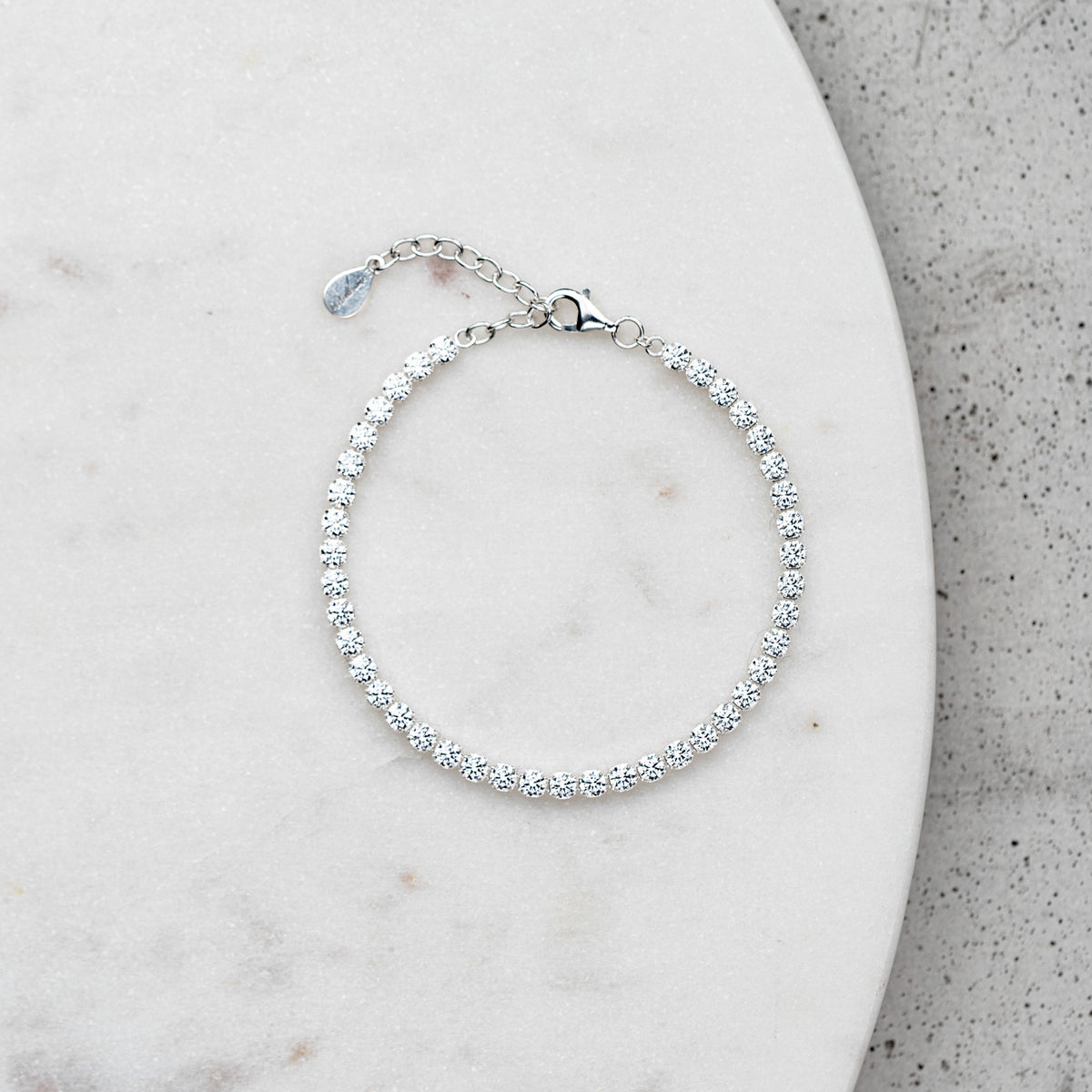 Brautarmband Sanna aus 925 Sterlingsilber mit durchgehender Reihe Zirkonia Kristallen, liegend auf Marmorplatte