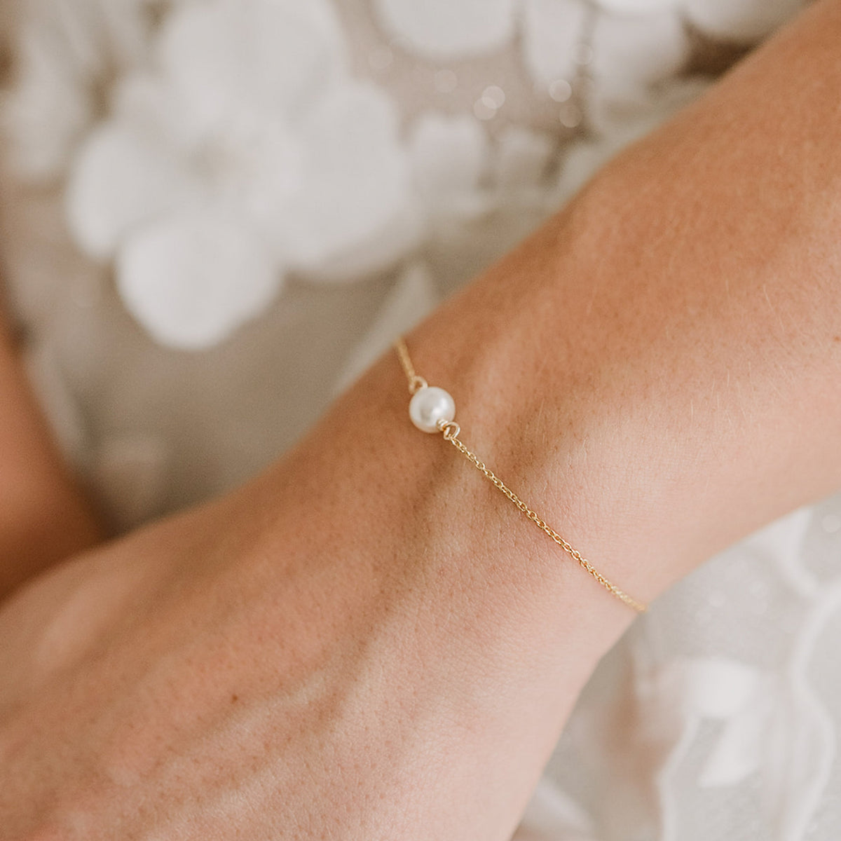 Brautarmband Valeria aus 925 Sterlingsilber 18K vergoldet mit hängenden veganen Perlen an einem Kettchen, verstellbar durch eine Stopperperle, am Model getragen in Nahaufnahme