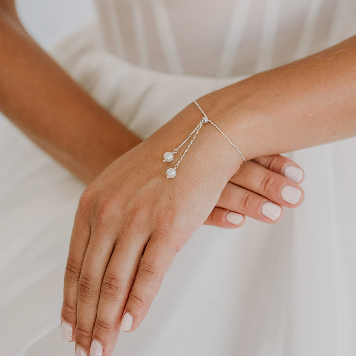 Brautarmband Valeria aus 925 Sterlingsilber mit hängenden veganen Perlen an einem Kettchen, verstellbar durch eine Stopperperle, am Model getragen in Nahaufnahme