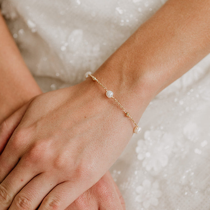 Edles Brautarmband Valli aus 925 Sterlingsilber 18K vergoldet mit echten Süßwasserperlen und kleinen Kugeln aus Metall, am Model getragen in Nahaufnahme