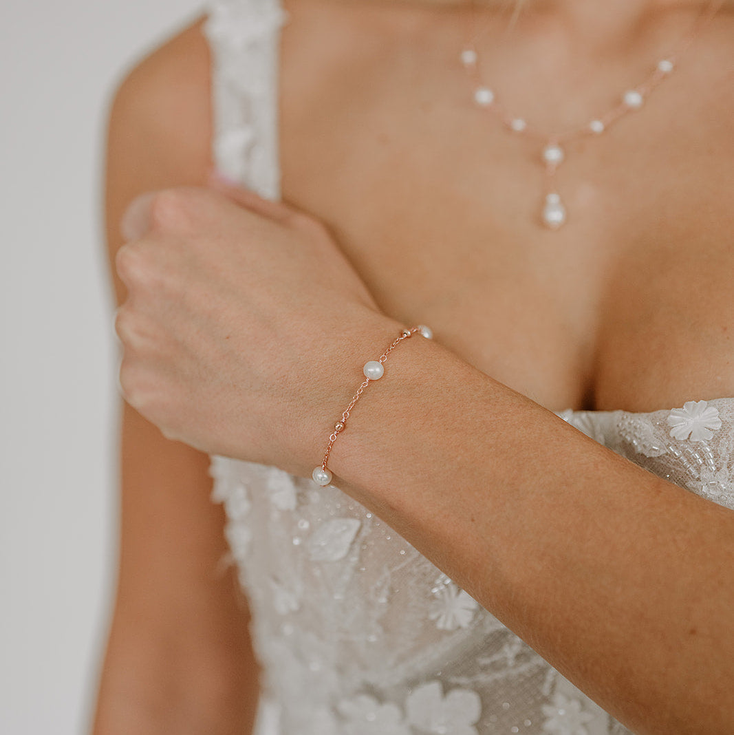 Edles Brautarmband Valli aus 925 Sterlingsilber 18K rosévergoldet mit echten Süßwasserperlen und kleinen Kugeln aus Metall, am Model getragen in Nahaufnahme