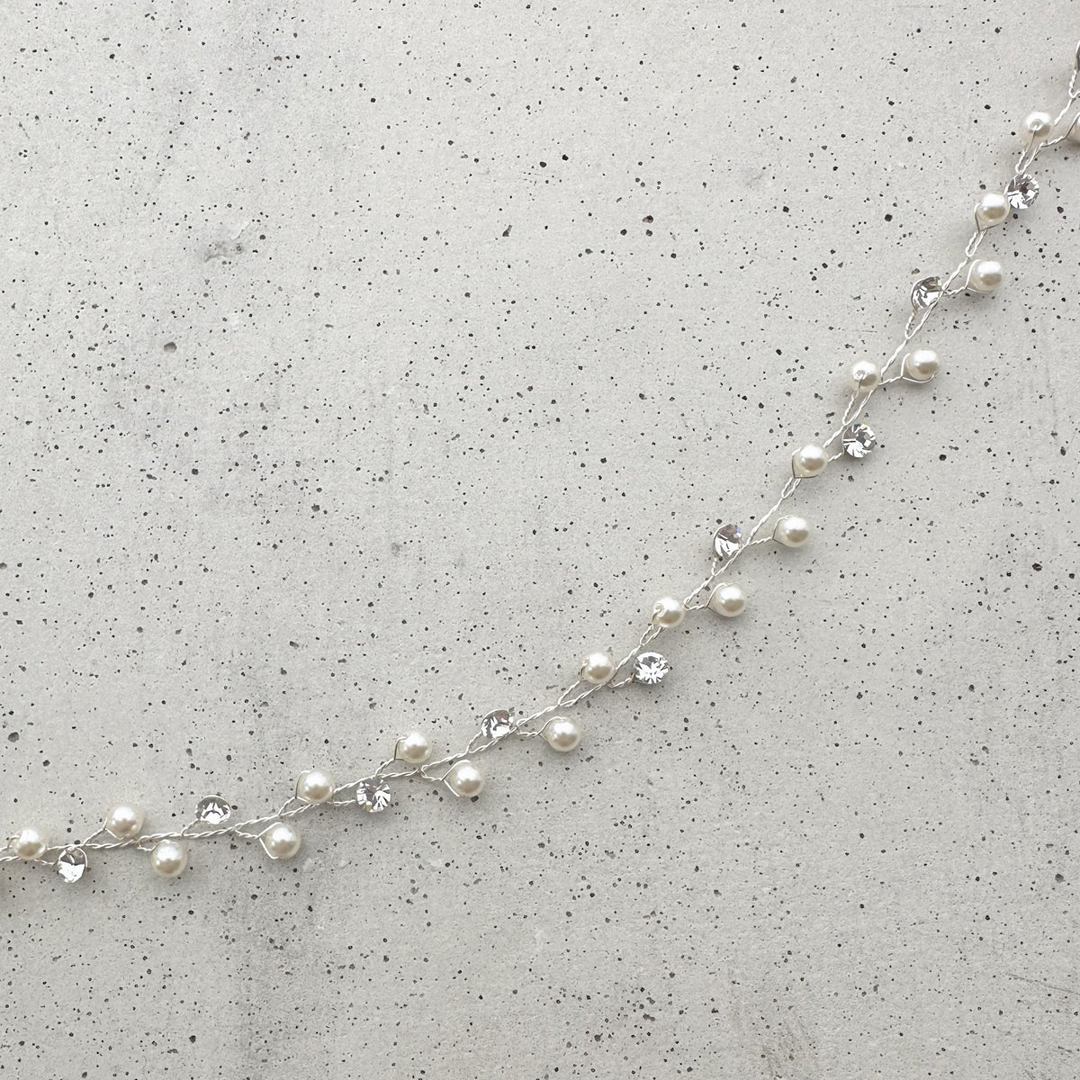 Braut Headpiece Basic III in Silber mit Perlen und Kristallen, Detailaufnahme liegend auf einer Betonplatte
