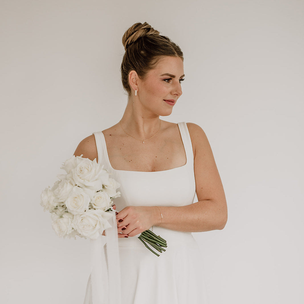 Braut Y-Kette Belina aus 925 Sterlingsilber 18K vergoldet – Rückenkette mit kleinen Perlen entlang der Kette und am Dekolleté ein kleiner Anhänger mit Perlen mit passenden Brautcreolen Belina und Brautarmband Belina, getragen vom Model mit Vorderansicht