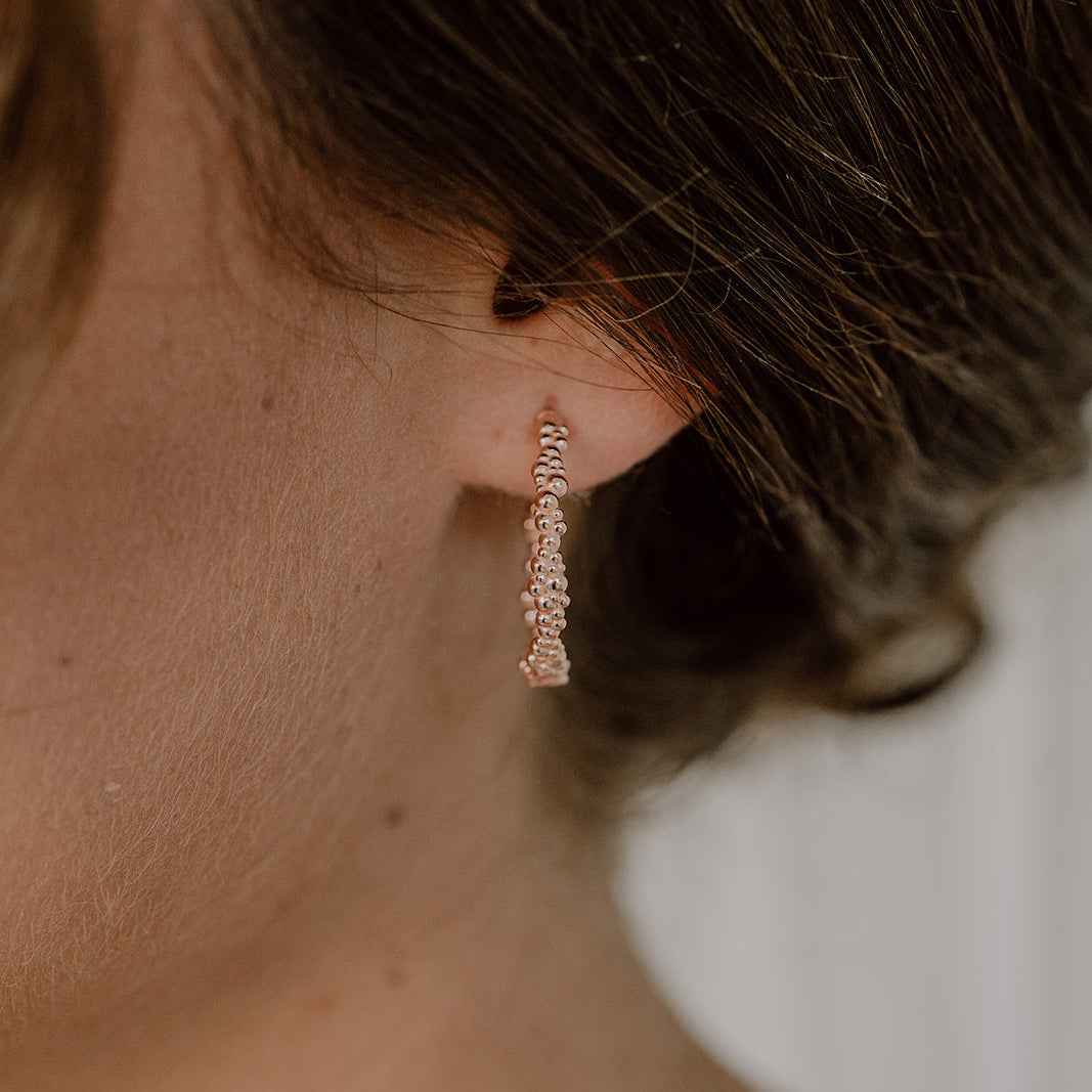 Schlichte Braut Creolen Kalli ohne Perle aus 925 Sterlingsilber 18K rosévergoldet, getragen von einem Model in Nahaufnahme