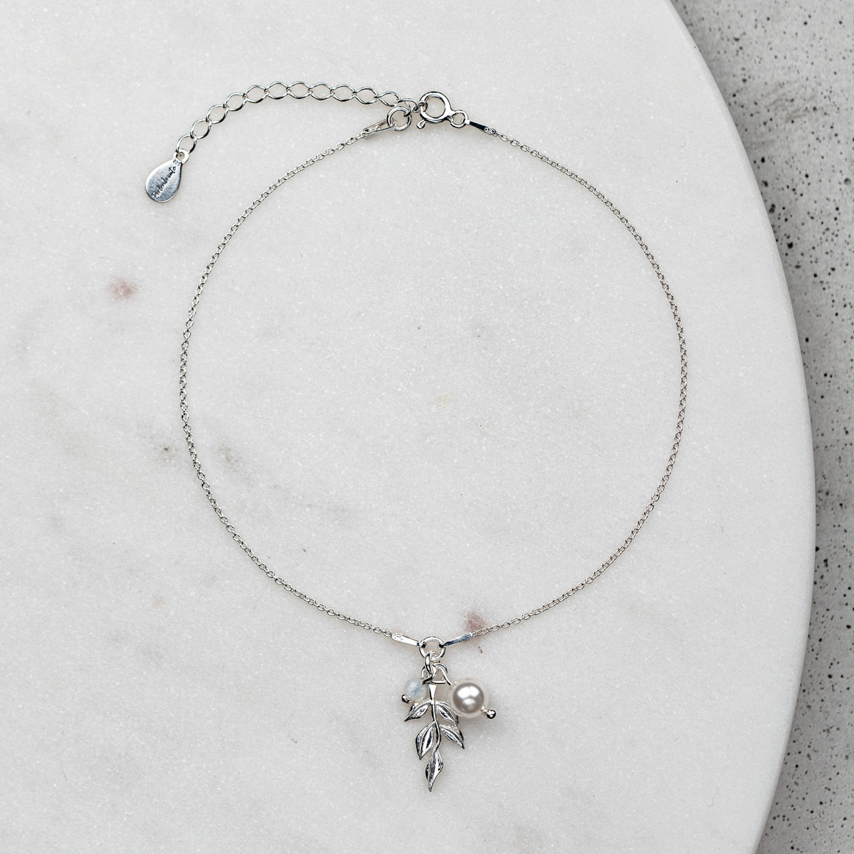 Braut Fußkettchen Resi aus 925 Sterlingsilber mit Blattanhänger, veganer Perle und Kristallperle, auf Marmorplatte