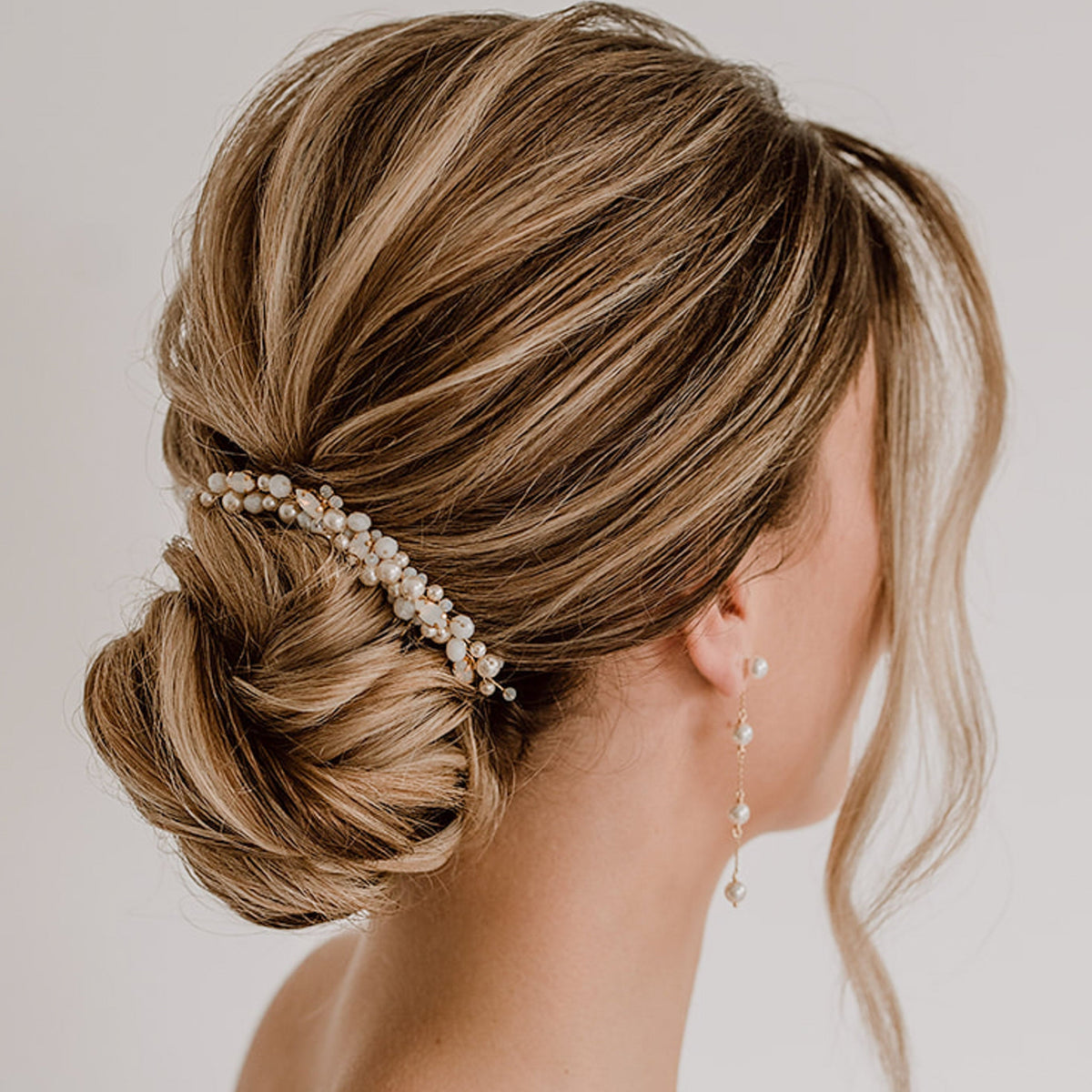 Braut Haarkamm Kylie in Gold mit veganen Perlen, Kristallperlen und white opal Kristallen, getragen von einem Model in einer hochgesteckten Brautfrisur