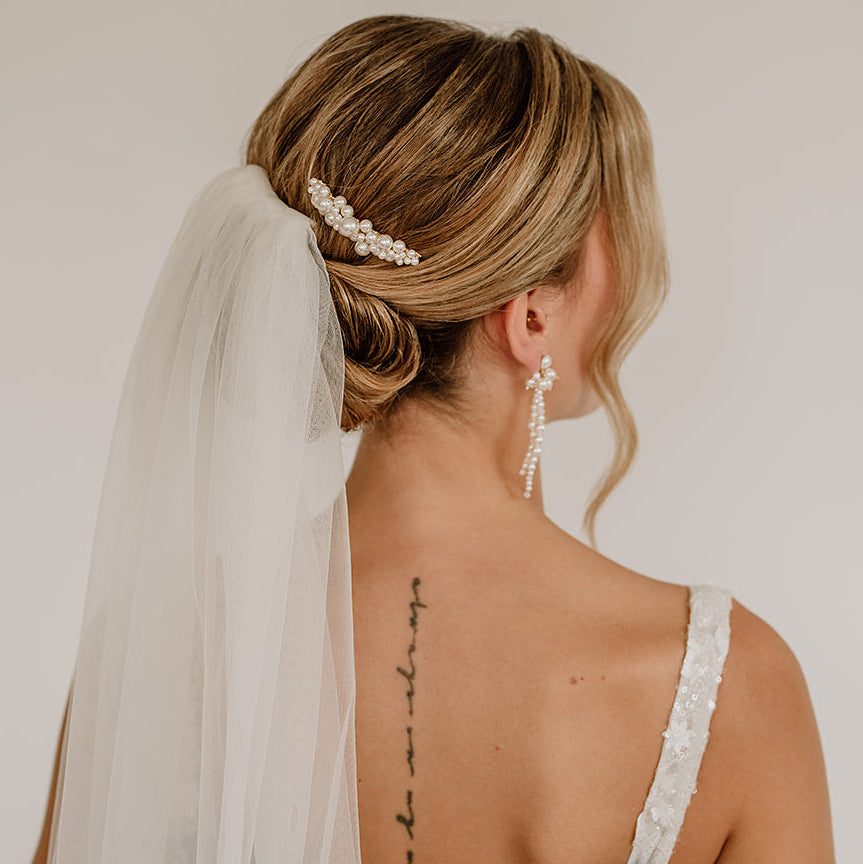 Braut Haarkamm Wilma in Gold mit unterschiedlich großen, veganen Perlen, getragen in einer eleganten Hochsteckfrisur mit Schleier