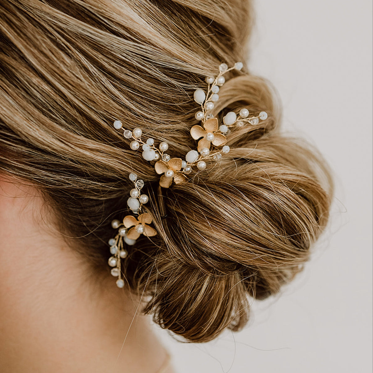 3er Set Braut Haarnadeln Babsi in Gold mit floralen Blüten, Kristallperlen und veganen Perlen, getragen in einer eleganten Hochsteckfrisur