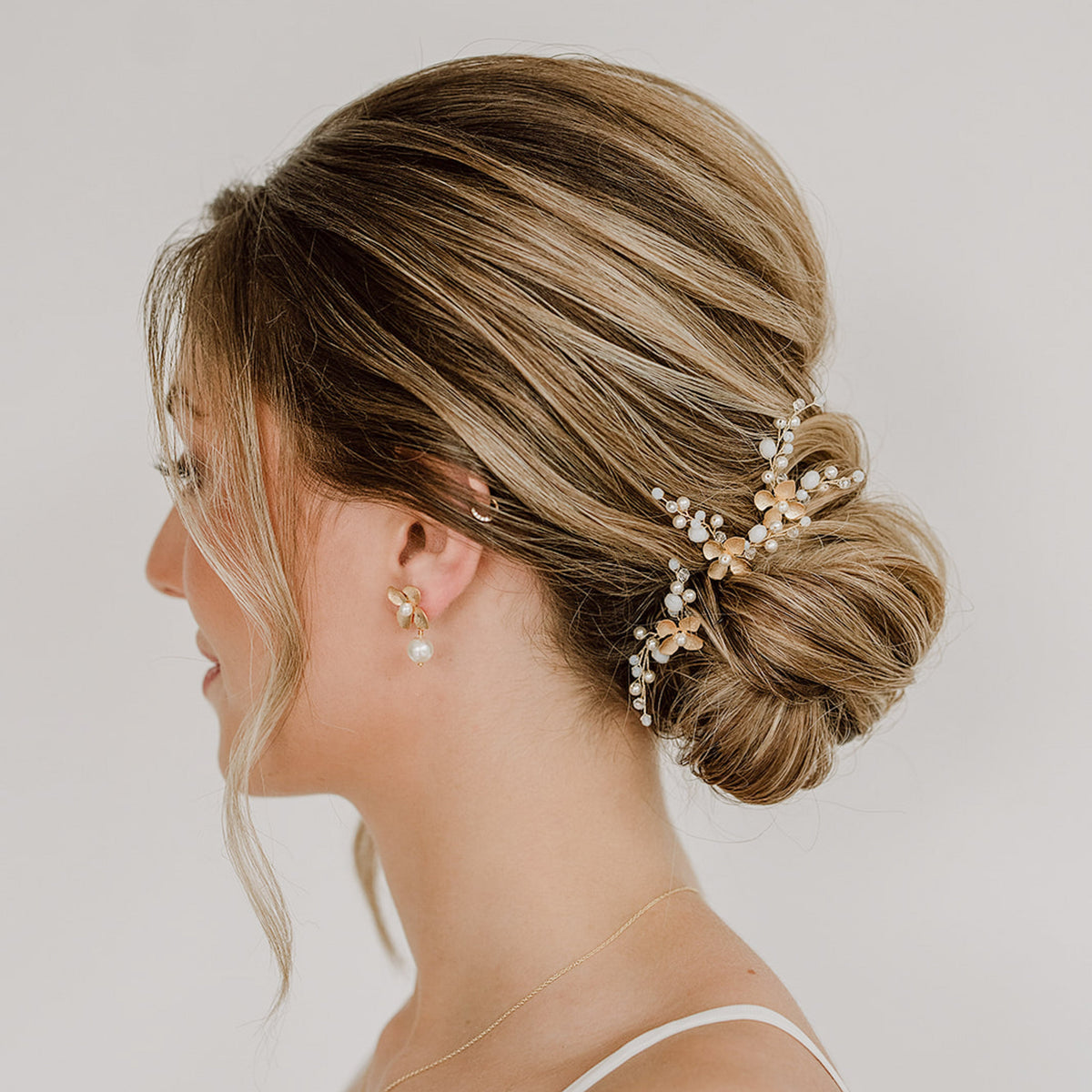 3er Set Braut Haarnadeln Babsi in Gold mit floralen Blüten, Kristallperlen und veganen Perlen, getragen in einer eleganten Hochsteckfrisur