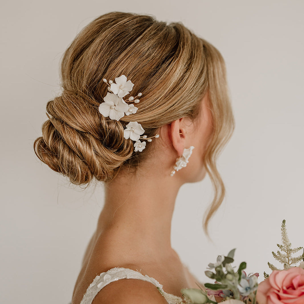 Braut Haarnadeln Coco in Gold mit weißen Porzellanblüten und echten Süßwasserperlen, getragen in einer eleganten Hochsteckfrisur
