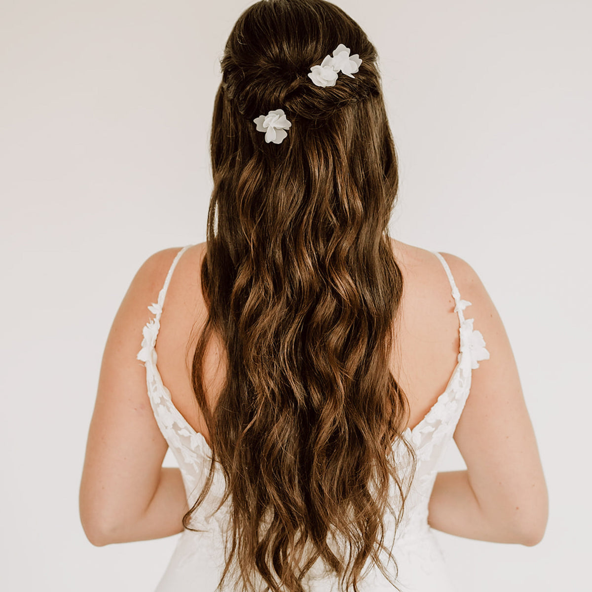 3er Set Braut Haarnadeln Flora in Silber mit weißen Stoffblüten, getragen von einem Model in einer halboffenen Brautfrisur
