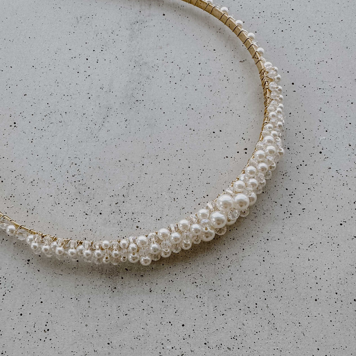 Braut Haarreif Lotte in Gold mit veganen Perlen und Kristallperlen, Detailaufnahme liegend auf einer Betonplatte