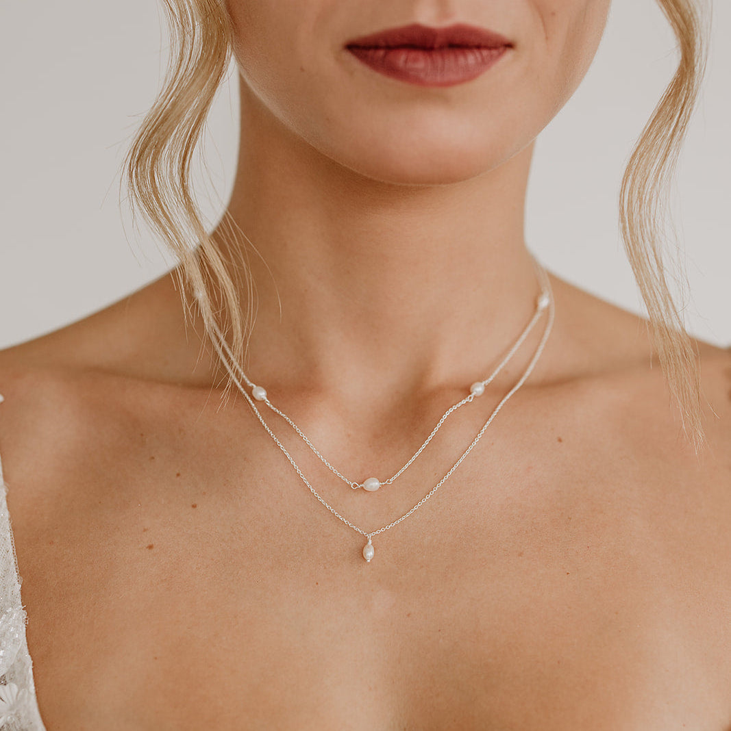 Zarte Brauthalskette Amelie aus 925 Sterlingsilber mit kleiner echter Süßwasserperle und Halskette Amaris im Layering Look, getragen von einem Model