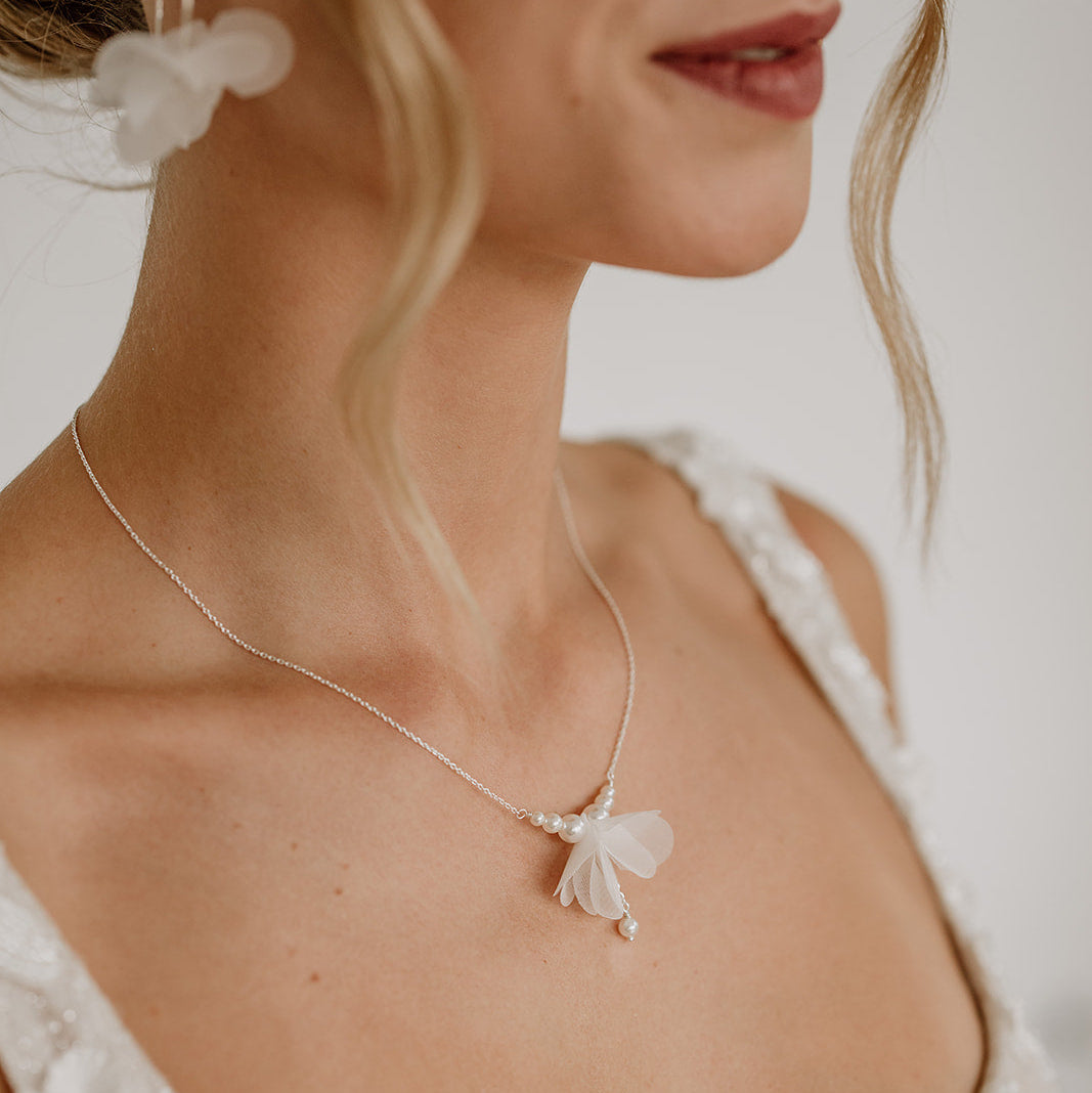 Brauthalskette Flora aus 925 Sterlingsilber mit weißer Stoffblüte und veganen Perlen, am Model getragen