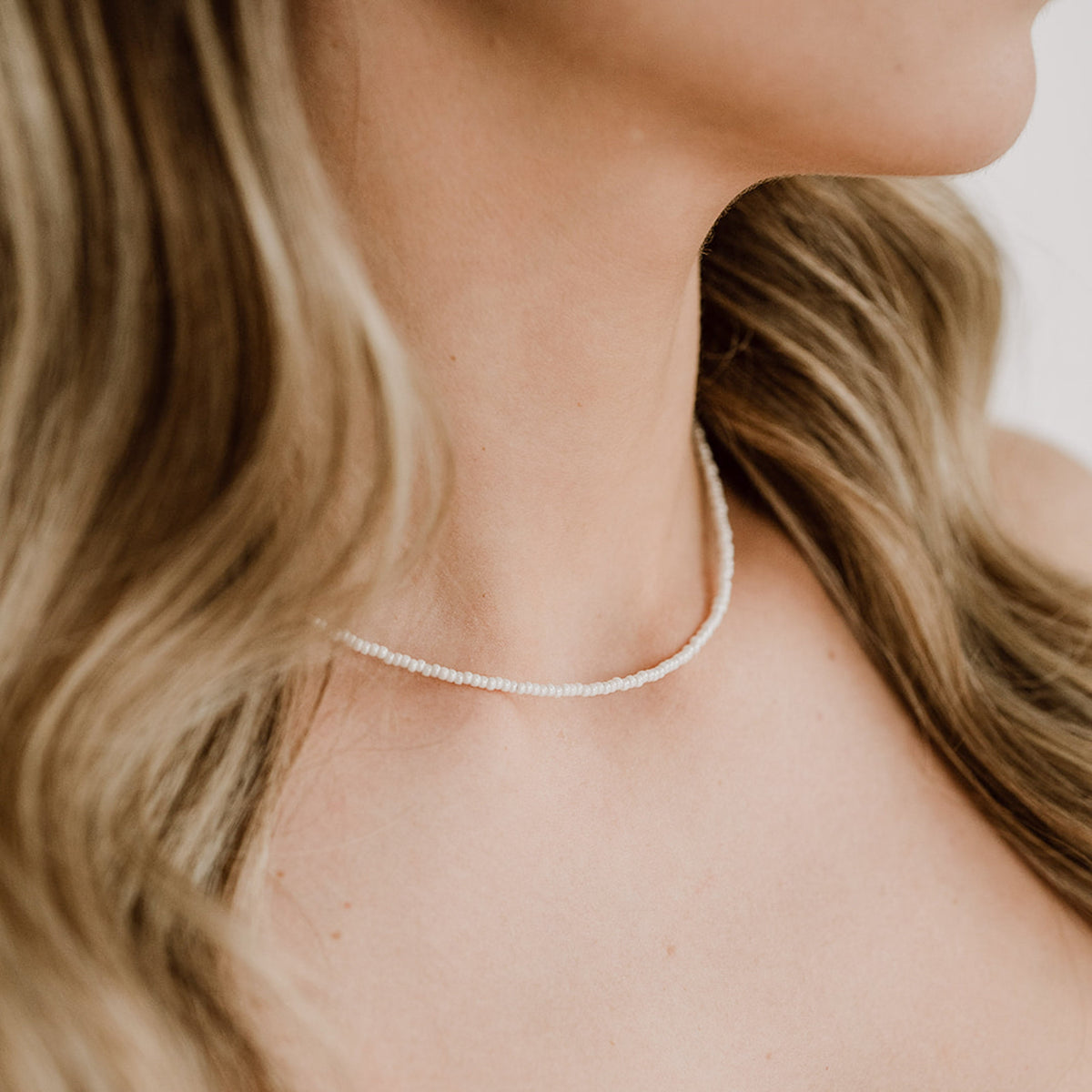 Zarte Brautperlenkette Lina mit kleinen veganen Perlen und 925 Sterlingsilber 18K vergoldetem Verschluss, am Model getragen in Nahaufnahme