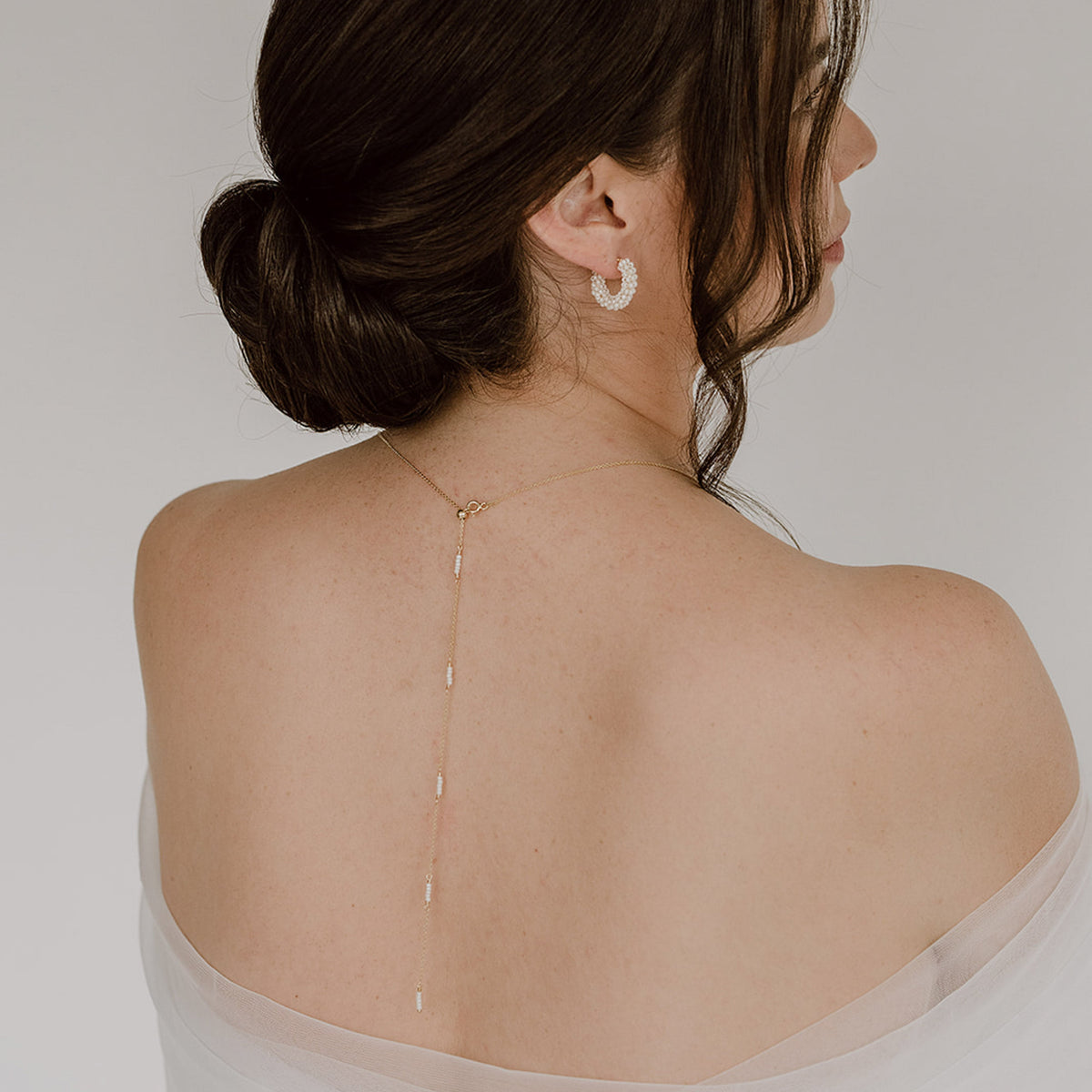 Braut Y-Kette Belina aus 925 Sterlingsilber 18K vergoldet – Rückenkette mit kleinen Perlen entlang der Kette und am Dekolleté ein kleiner Anhänger mit Perlen mit passenden Brautcreolen Belina, getragen vom Model mit Rückansicht