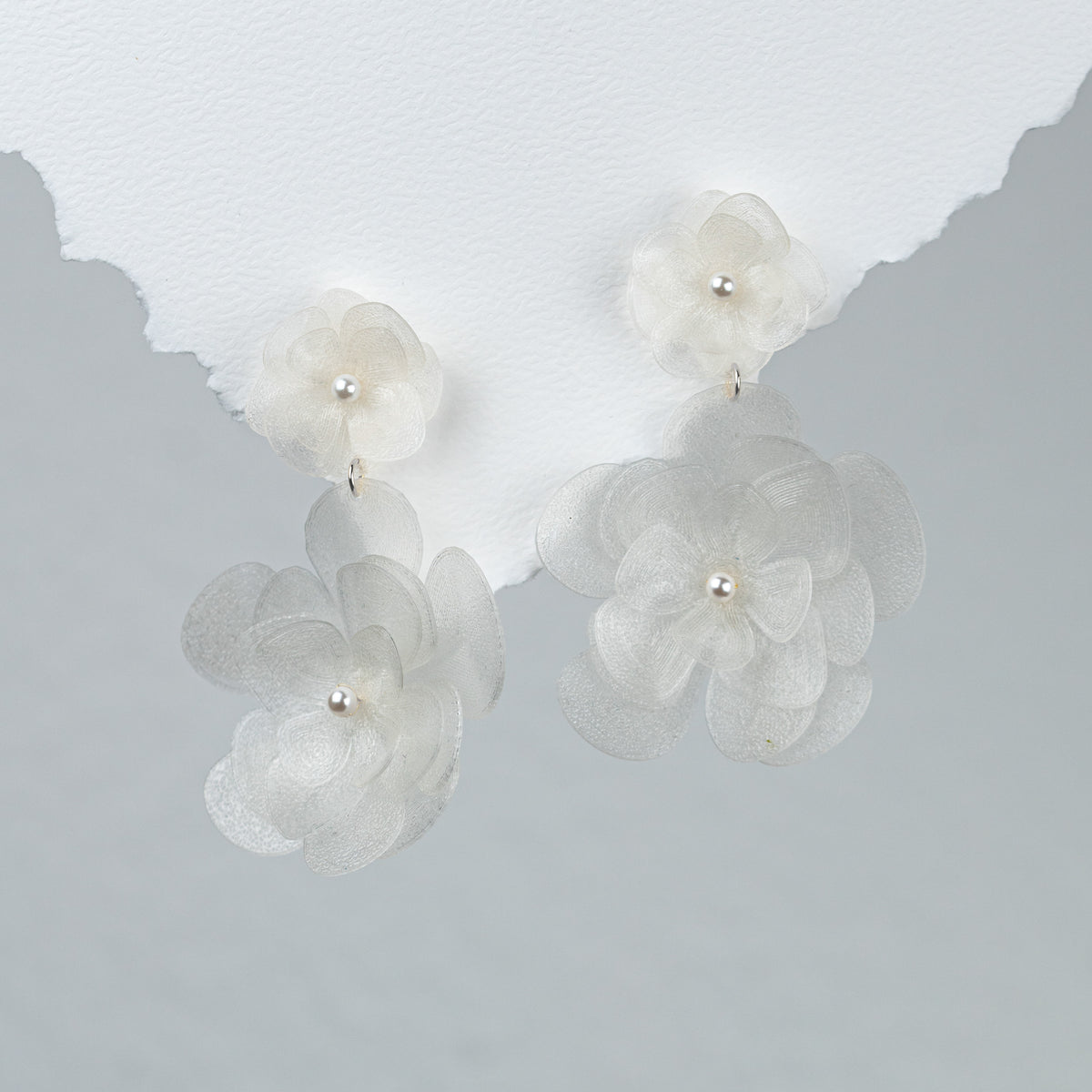 Elegante Statement Brautohrringe aus 925er Sterlingsilber mit einer großen und einer kleinen, hängenden Blüte, detailreich dargestellt auf einem weißen Hintergrund.