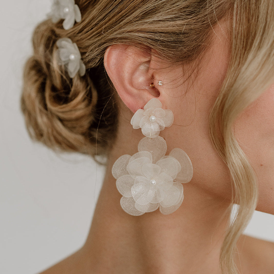 Elegante Statement Brautohrringe aus 925er Sterlingsilber 18K vergoldet mit einer großen und einer kleinen, hängenden Blüte, detailreich dargestellt am Ohr.