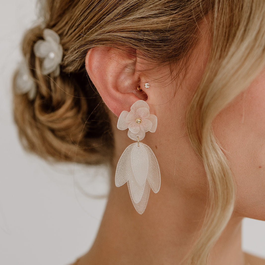 Hängende Statement Brautohrringe Chiara mit weißen Blüten aus biobasiertem, nachhaltigen Material, aus 925 Sterlingsilber 18K vergoldet, am Model getragen