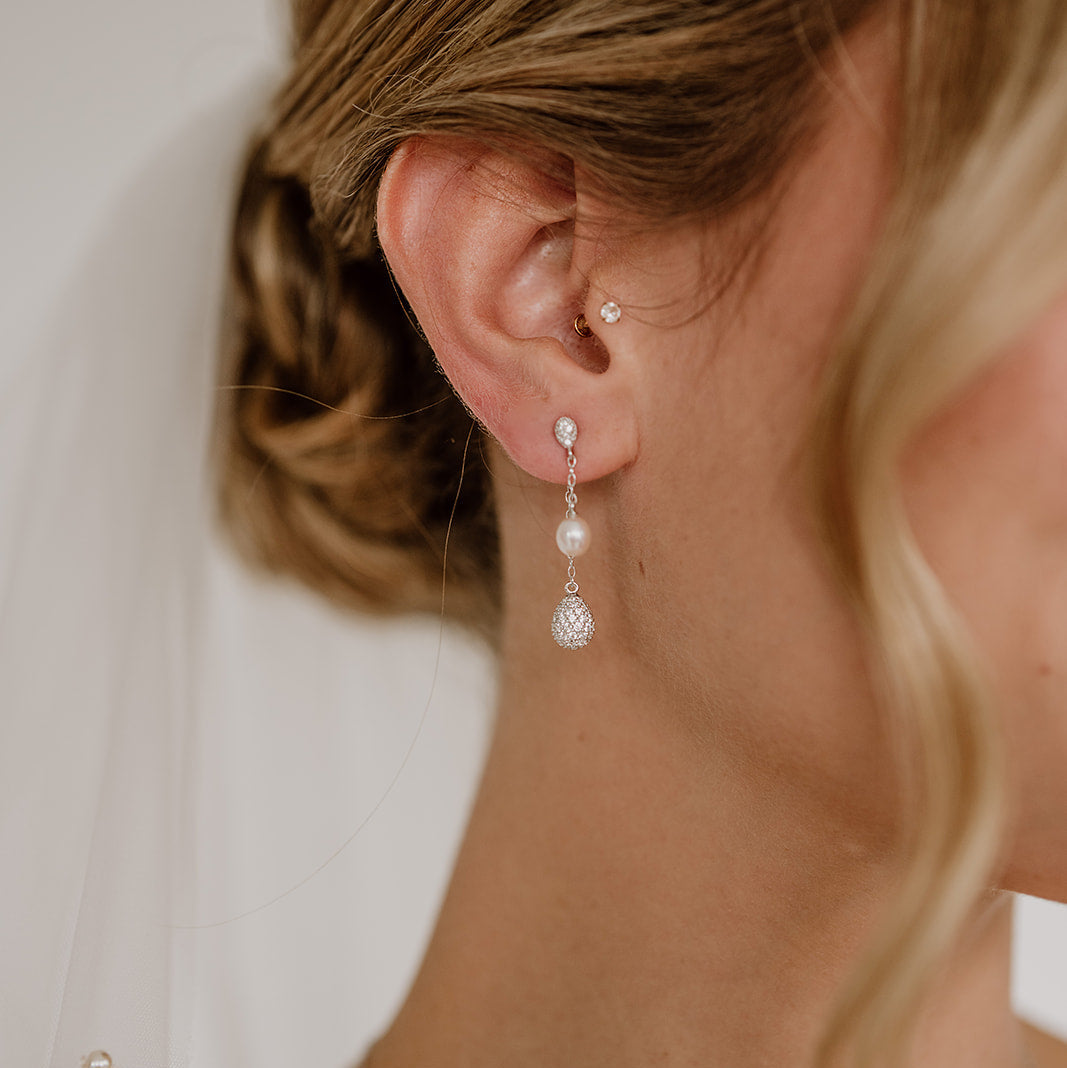 Brautohrringe Elaine aus 925 Sterlingsilber mit echter Süßwasserperle und einem Tropfen besetzt mit Zirkonia Kristallen an einem feinen Kettchen, am Model getragen