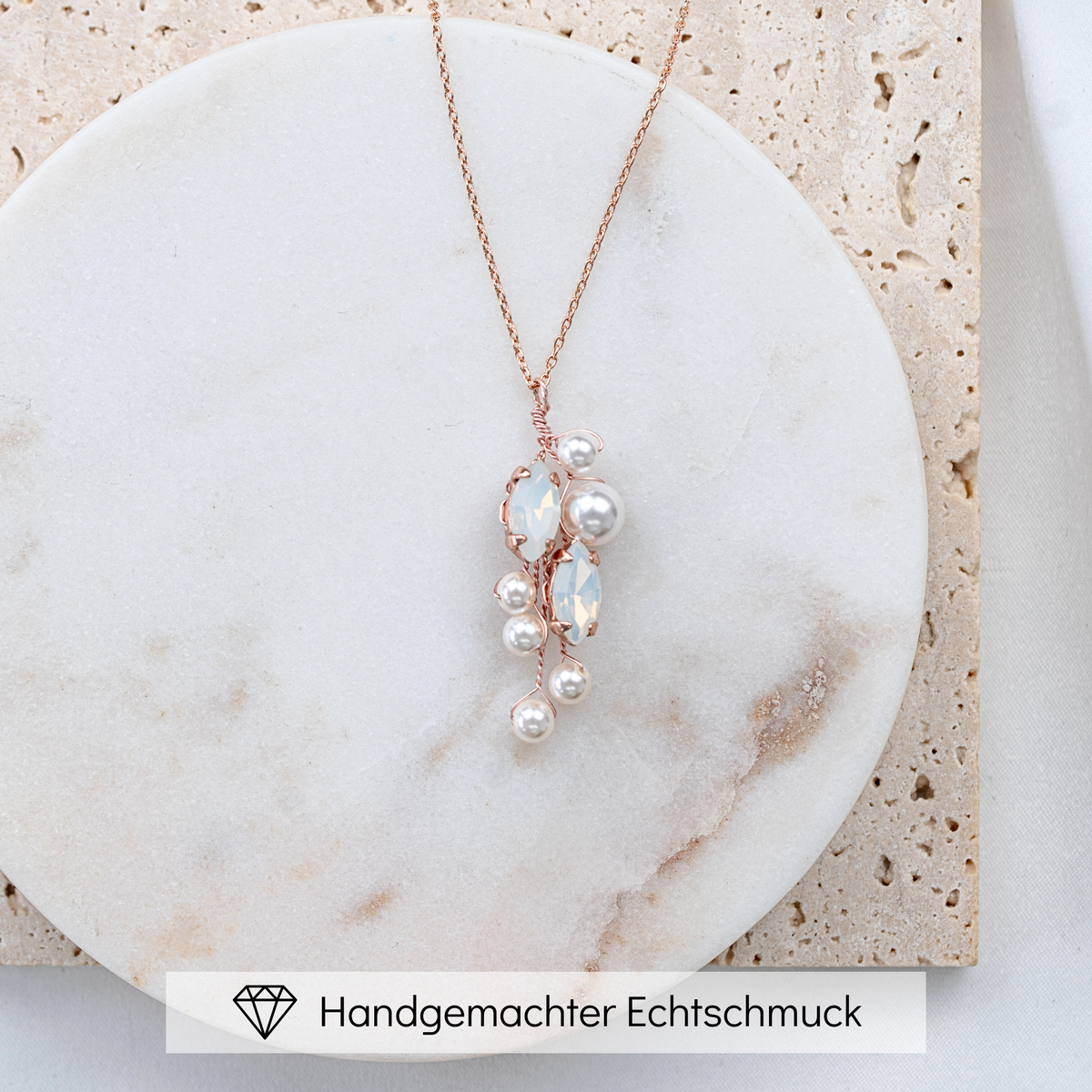 Brauthalskette Anastasia aus 925 Sterlingsilber 18K rosévergoldet mit veganen Perlen und blattförmigen white opal Kristallen, liegend auf Marmorplatte