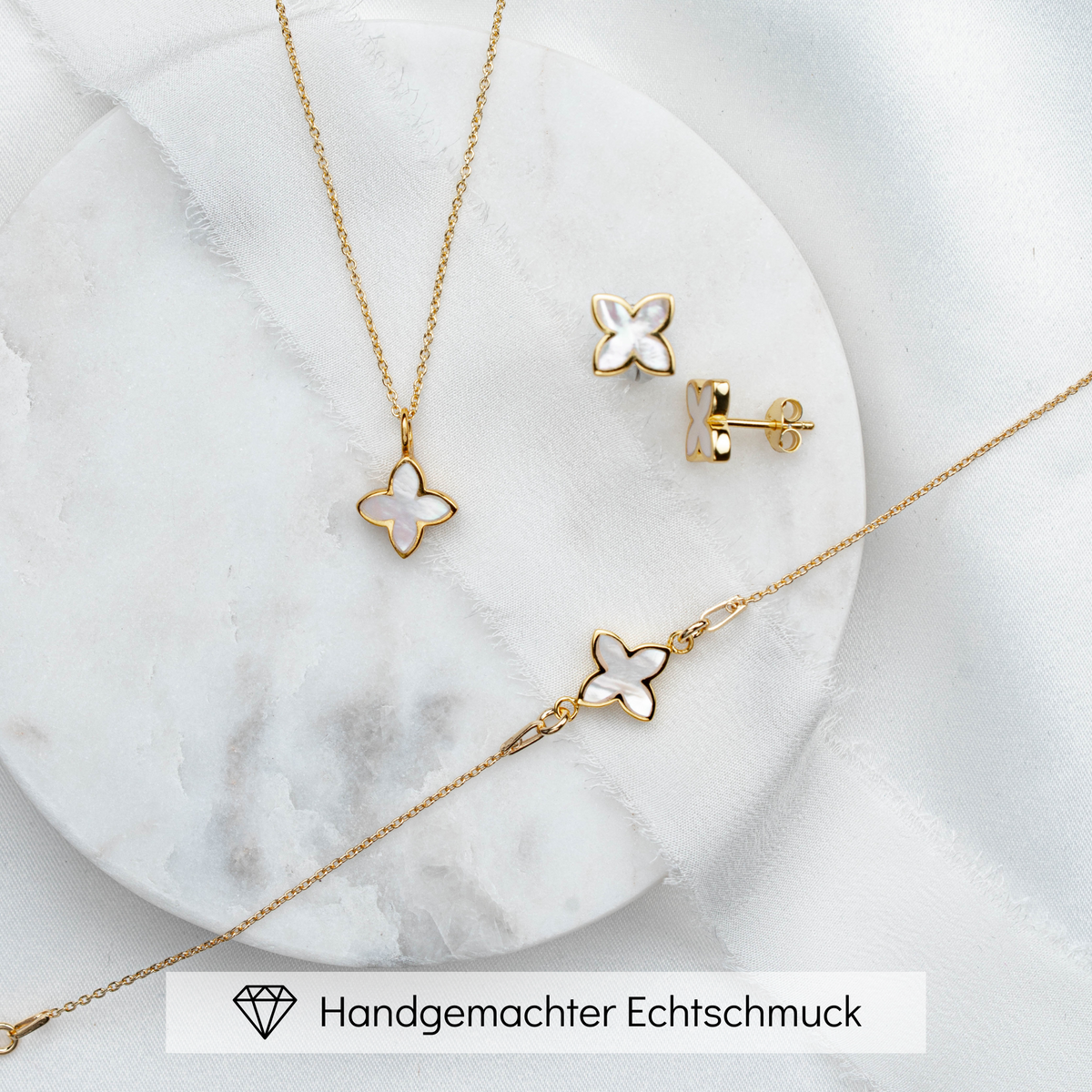 3-teiliges Brautschmuckset Daisy aus 925 Sterlingsilber 18K vergoldet – Ohrringe, Halskette und Armband mit perlmuttfarbener Blüte, auf Marmorplatte