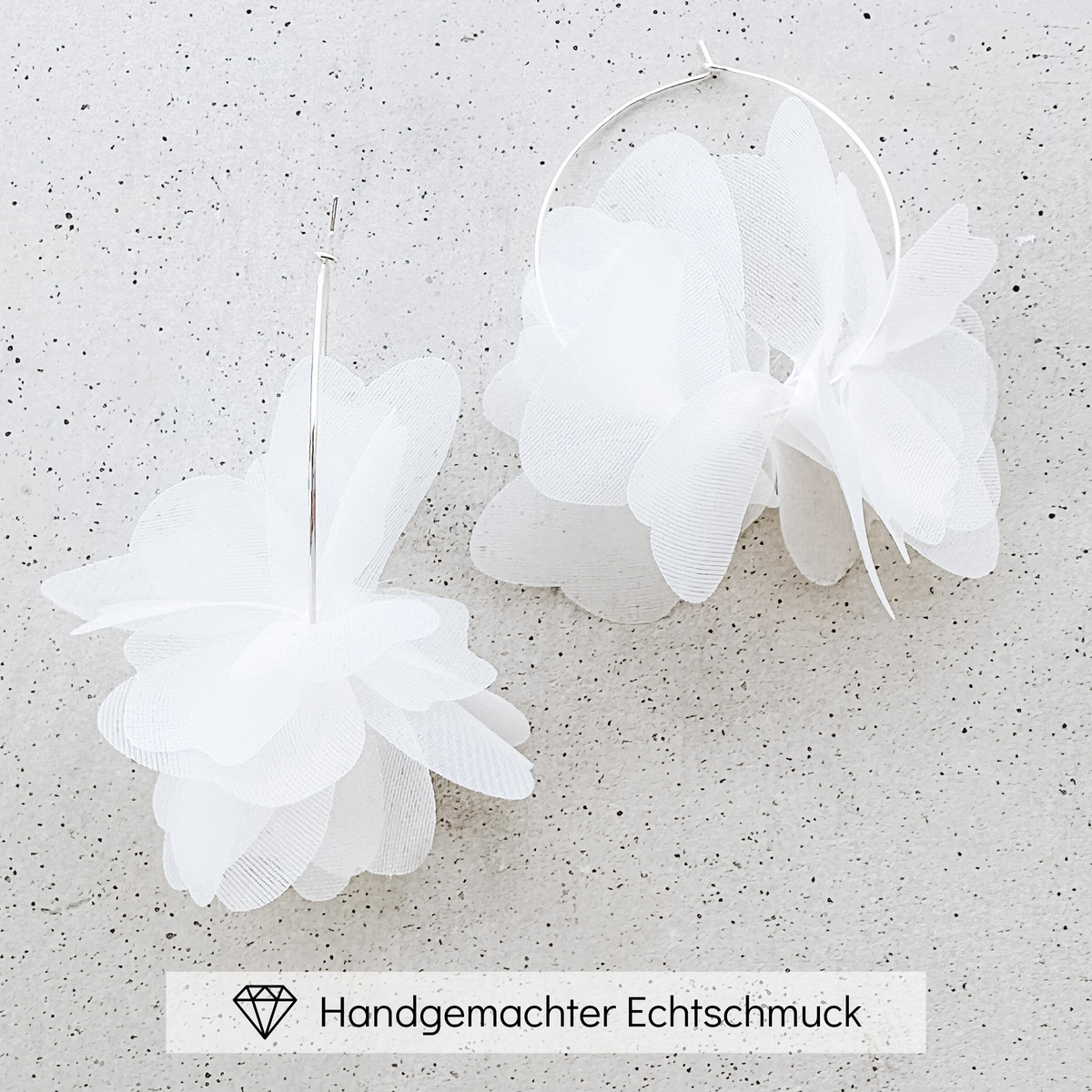 Braut Creolen Flora aus 925 Sterlingsilber mit weißen Stoffblüten, liegend auf einer Steinplatte, handgefertigt