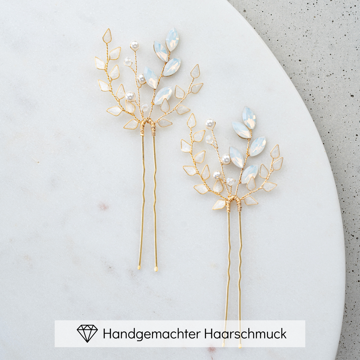 Braut Haarnadeln Gretchen in Gold mit ivoryfarbenen Blättern, white opal Kristallen in Blattform, veganen Perlen und Kristallperlen, liegend auf Marmorplatte