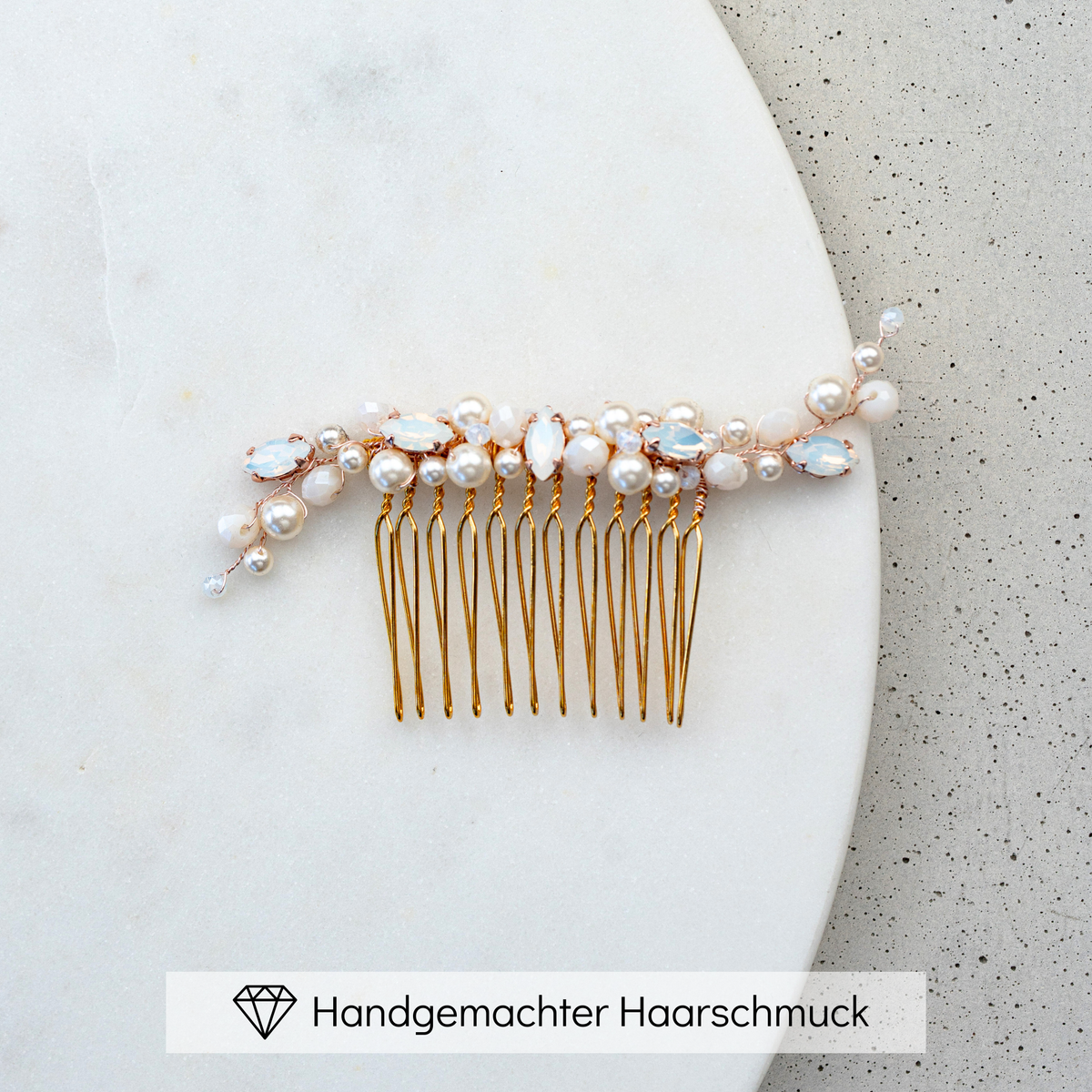 Braut Haarkamm Kylie in Roségold mit veganen Perlen, Kristallperlen und white opal Kristallen, liegend auf einer Marmorplatte