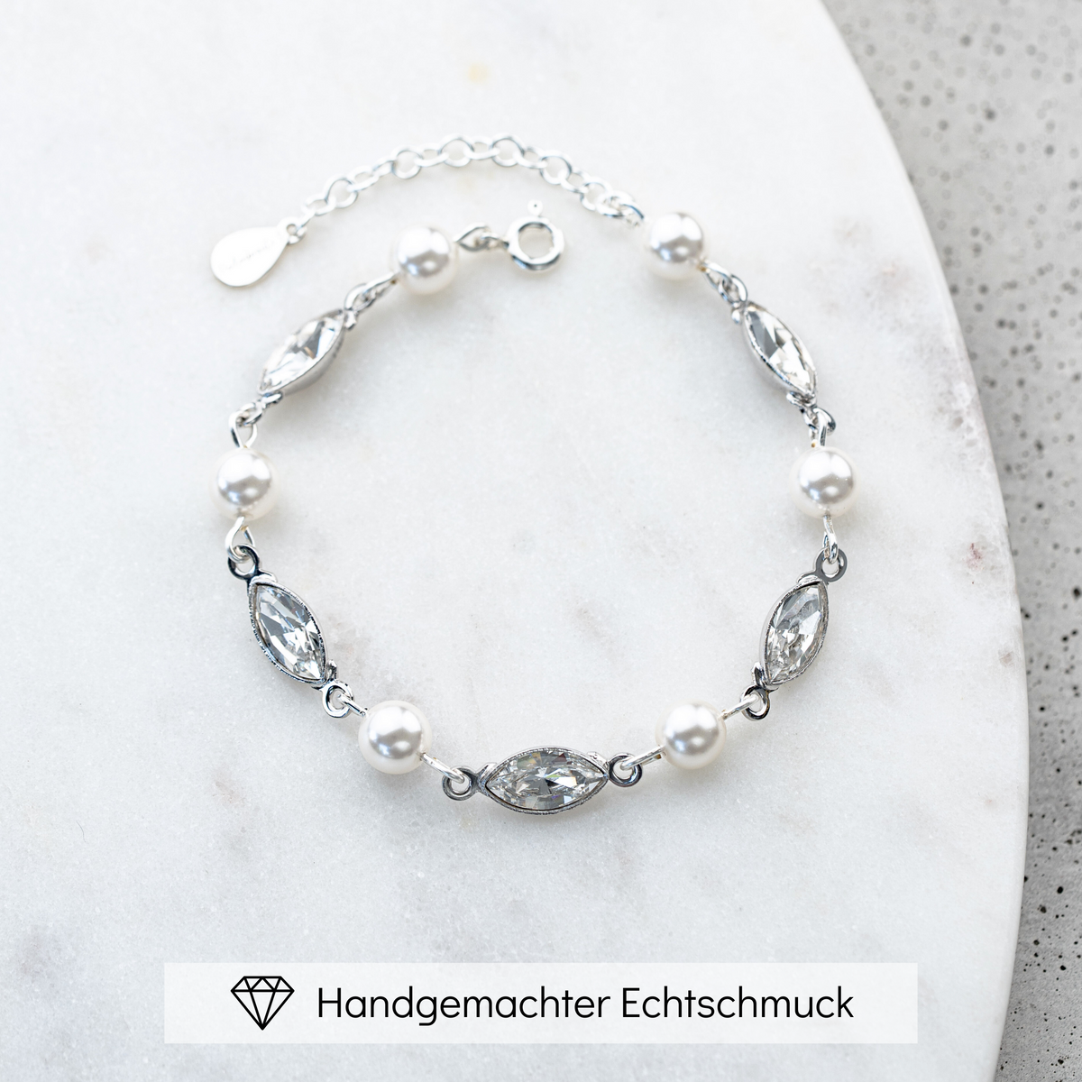 Brautarmband Kylie aus 925 Sterlingsilber mit veganen Perlen und crystal Kristallen im Wechsel, liegend auf einer Marmorplatte