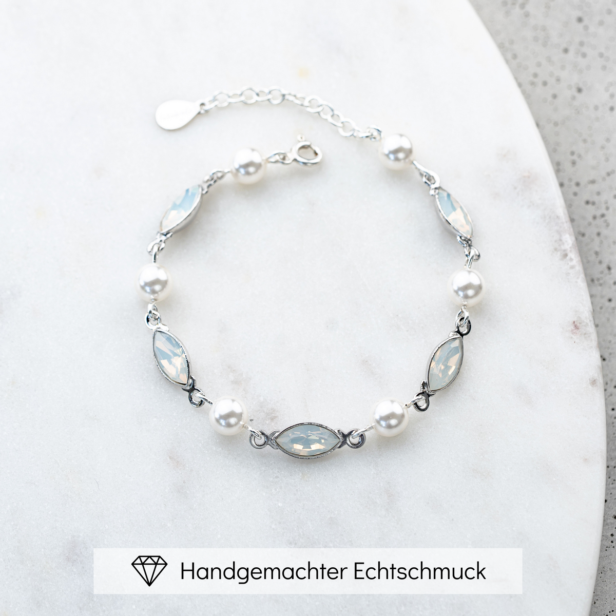 Brautarmband Kylie aus 925 Sterlingsilber mit veganen Perlen und white opal Kristallen im Wechsel, liegend auf einer Marmorplatte