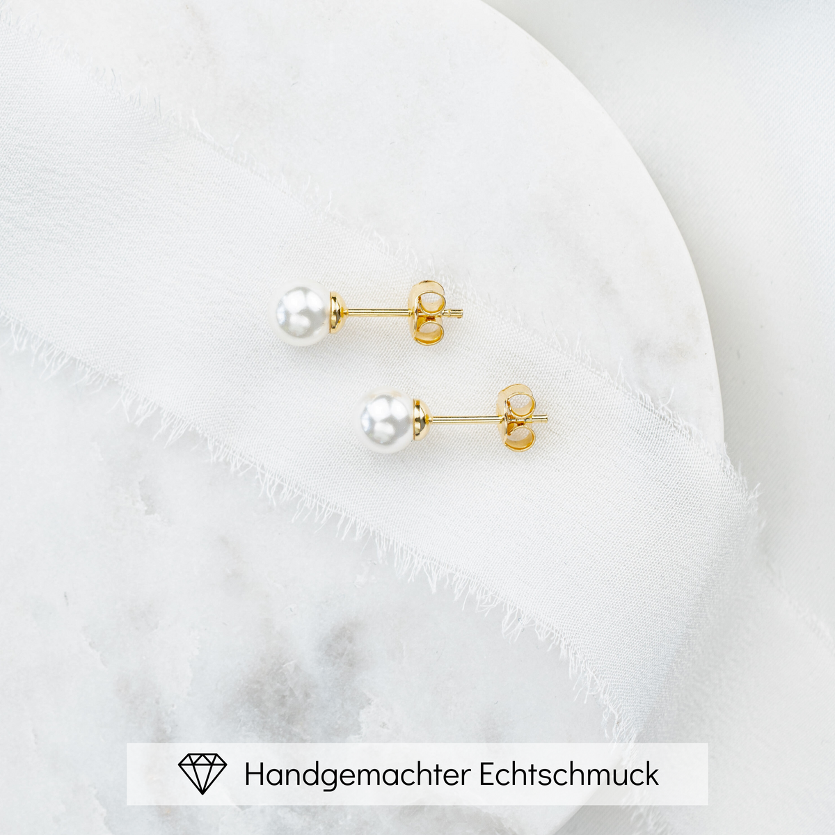 Perlenstecker Perla 6mm aus 925 Sterlingsilber 18K vergoldet mit veganer Perle, Seitenansicht, liegend auf einer Marmorplatte