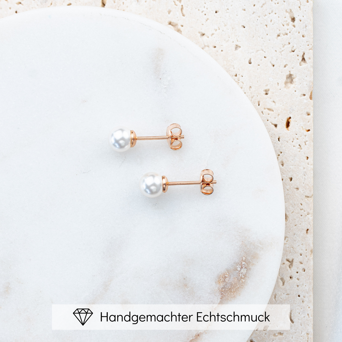 Perlenstecker Perla 6mm aus 925 Sterlingsilber 18K rosévergoldet mit veganer Perle, Seitenansicht, liegend auf einer Marmorplatte