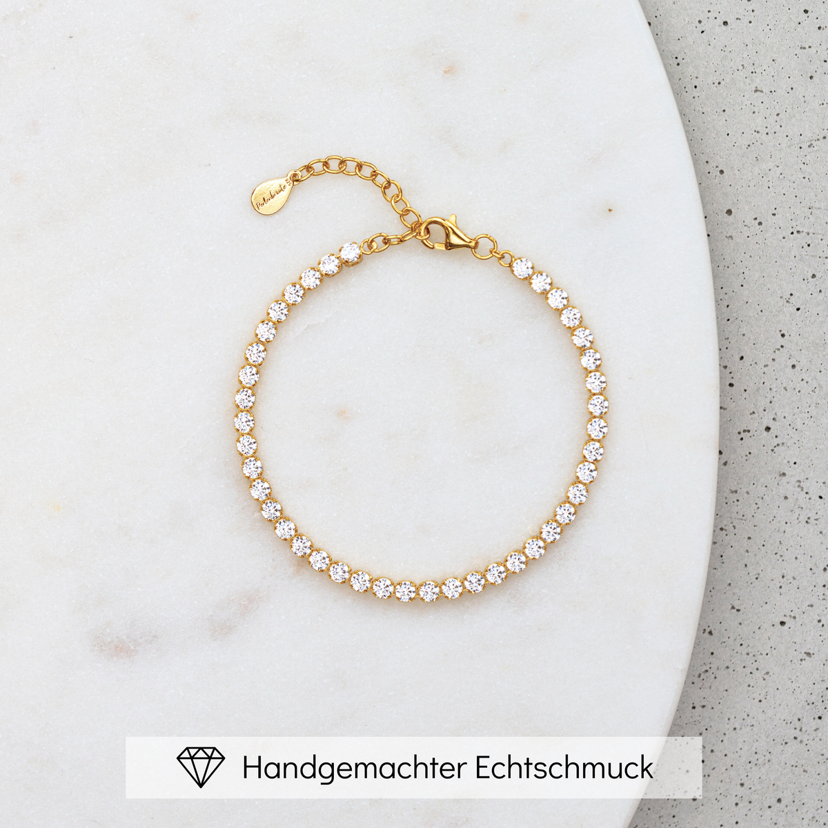 Brautarmband Sanna aus 925 Sterlingsilber 18K vergoldet mit durchgehender Reihe Zirkonia Kristallen, liegend auf Marmorplatte