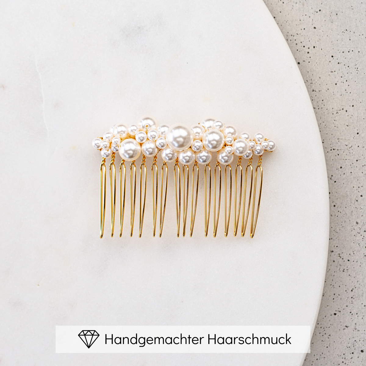 Braut Haarkamm Wilma in Gold mit unterschiedlich großen, veganen Perlen, liegend auf einer Marmorplatte