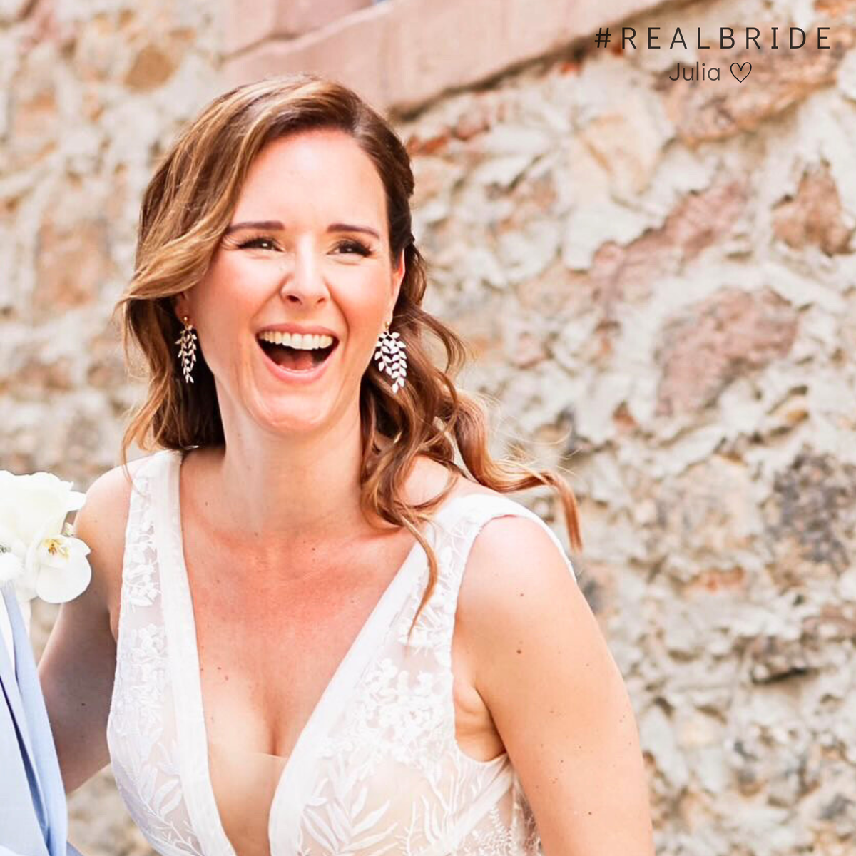 Geschmackvolle hängende Brautohrringe aus 925er Sterlingsilber 18K vergoldet mit ivory farbigen, blattförmigen Ranken, stilvoll getragen von einer Real Bride, die vor Freude strahlt, und harmonisch kombiniert mit einer romantischen Brautfrisur.
