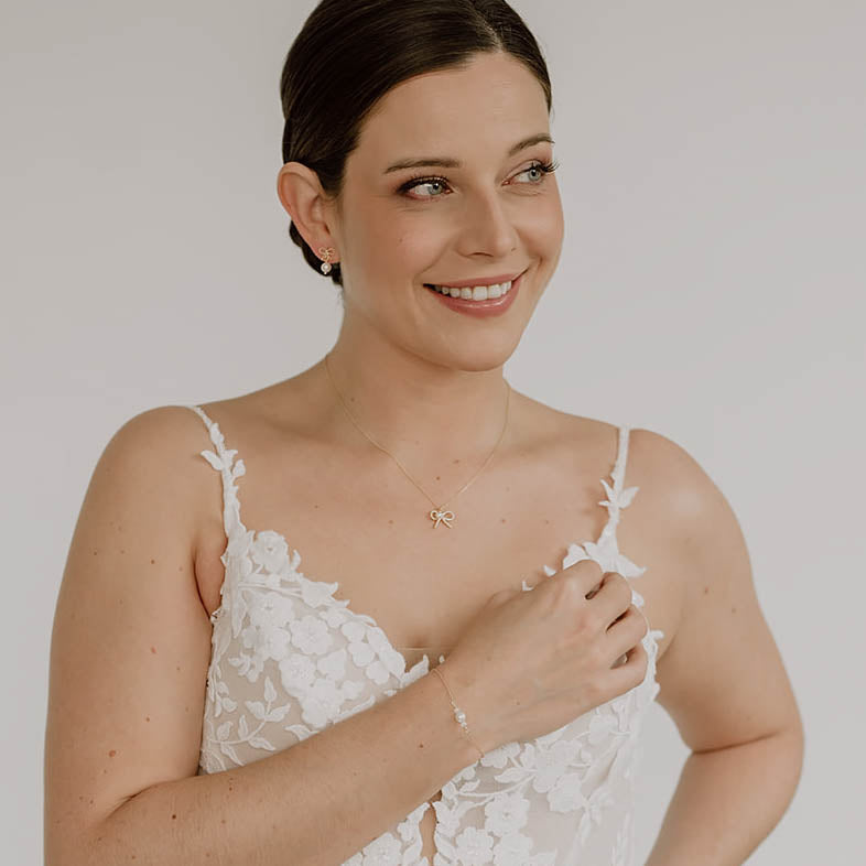 Braut Ohrringe Pinella, Schleifen Ohrstecker mit veganer Perle in 925 Sterlingsilber 18K vergoldet mit passender Braut Halskette Pinella und Braut Armband Ari, getragen am Model