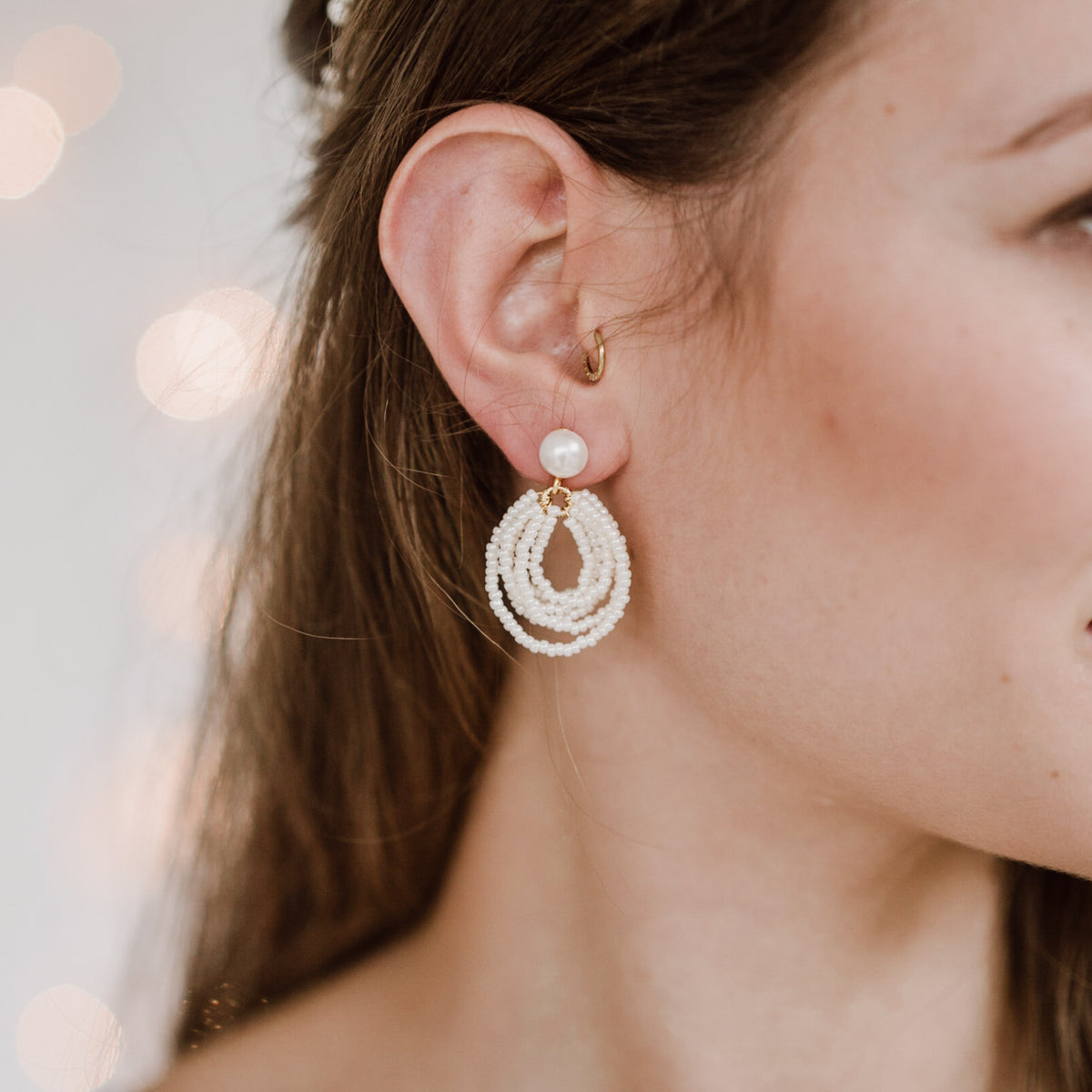 Brautohrringe Gigi aus 925 Sterlingsilber 18K vergoldet mit Perlenstecker und hängenden, kleinen Perlen in mehrreihiger Tropfenform, am Model getragen in Nahaufnahme