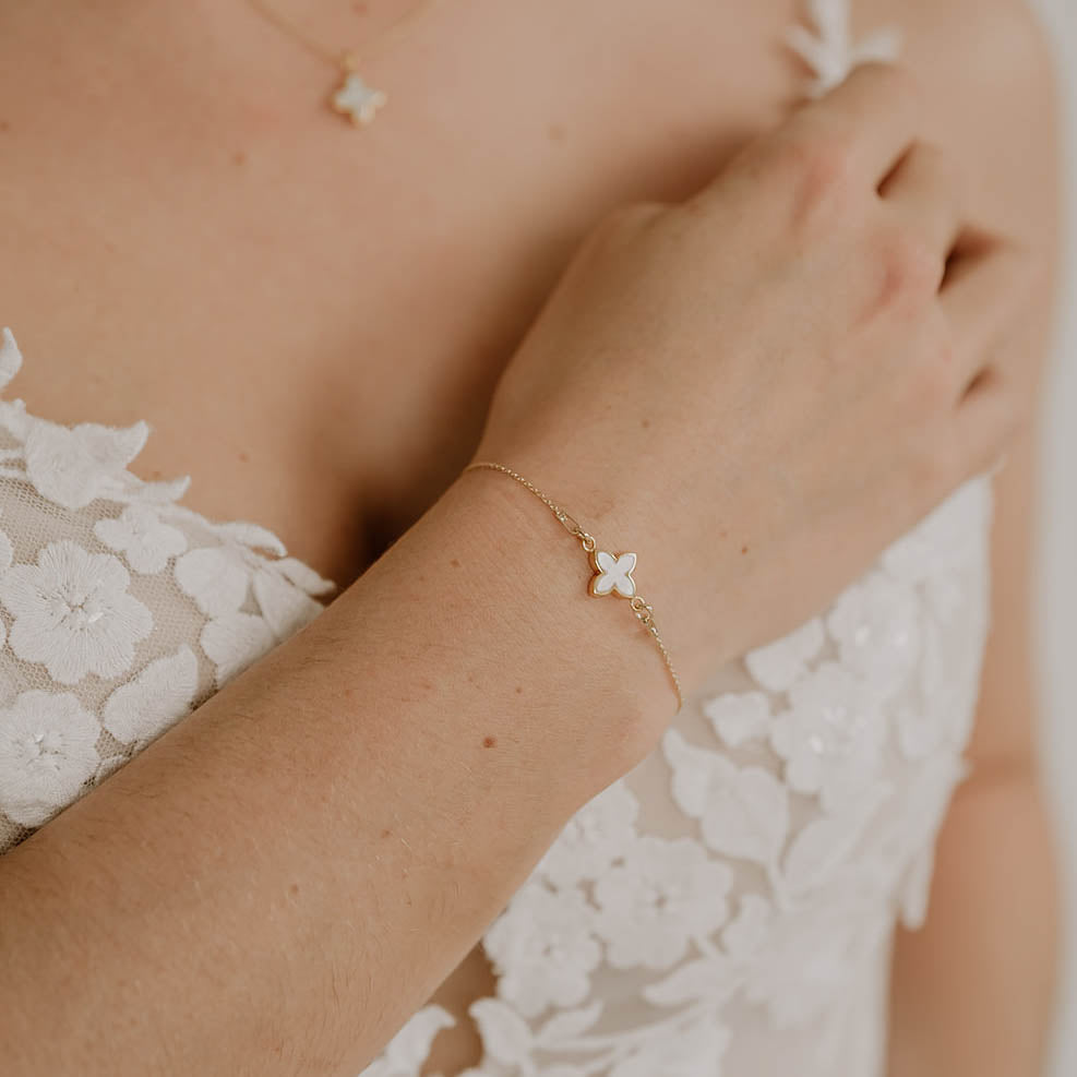 Brautarmband Daisy aus 925 Sterlingsilber 18K vergoldet mit kleiner perlmuttfarbener Blüte, am Model getragen in Nahaufnahme