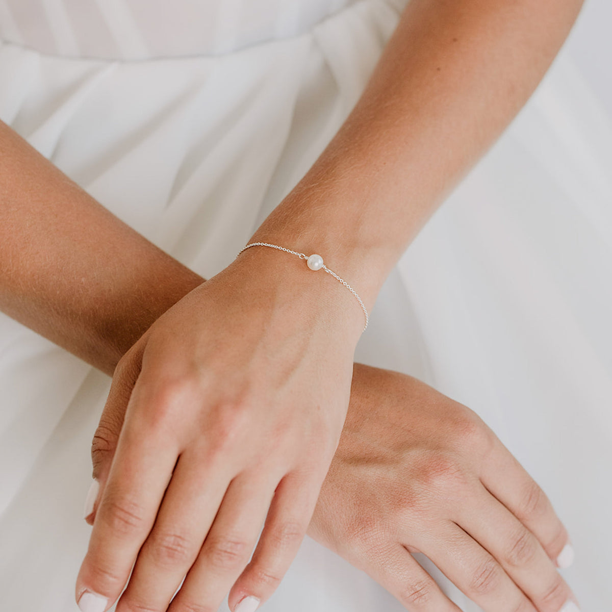 Brautarmband Valeria aus 925 Sterlingsilber mit hängenden veganen Perlen an einem Kettchen, verstellbar durch eine Stopperperle, am Model getragen in Nahaufnahme