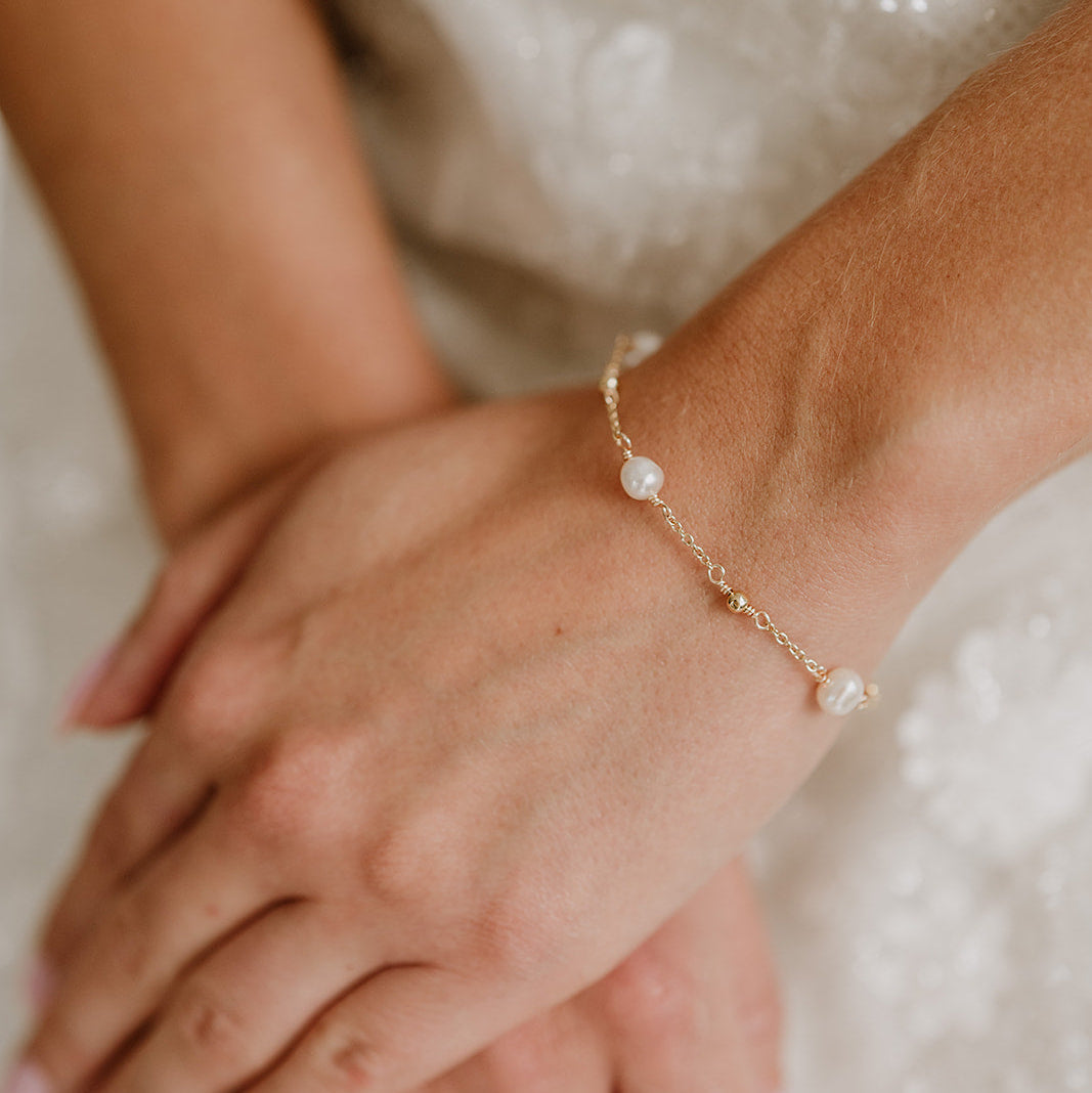 Edles Brautarmband Valli aus 925 Sterlingsilber 18K vergoldet mit echten Süßwasserperlen und kleinen Kugeln aus Metall, am Model getragen in Nahaufnahme