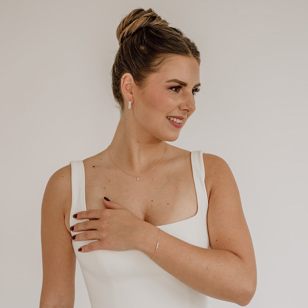Braut Y-Kette Belina aus 925 Sterlingsilber 18K vergoldet – Rückenkette mit kleinen Perlen entlang der Kette und am Dekolleté ein kleiner Anhänger mit Perlen mit passenden Brautcreolen Belina und Brautarmband Belina, getragen vom Model mit Vorderansicht