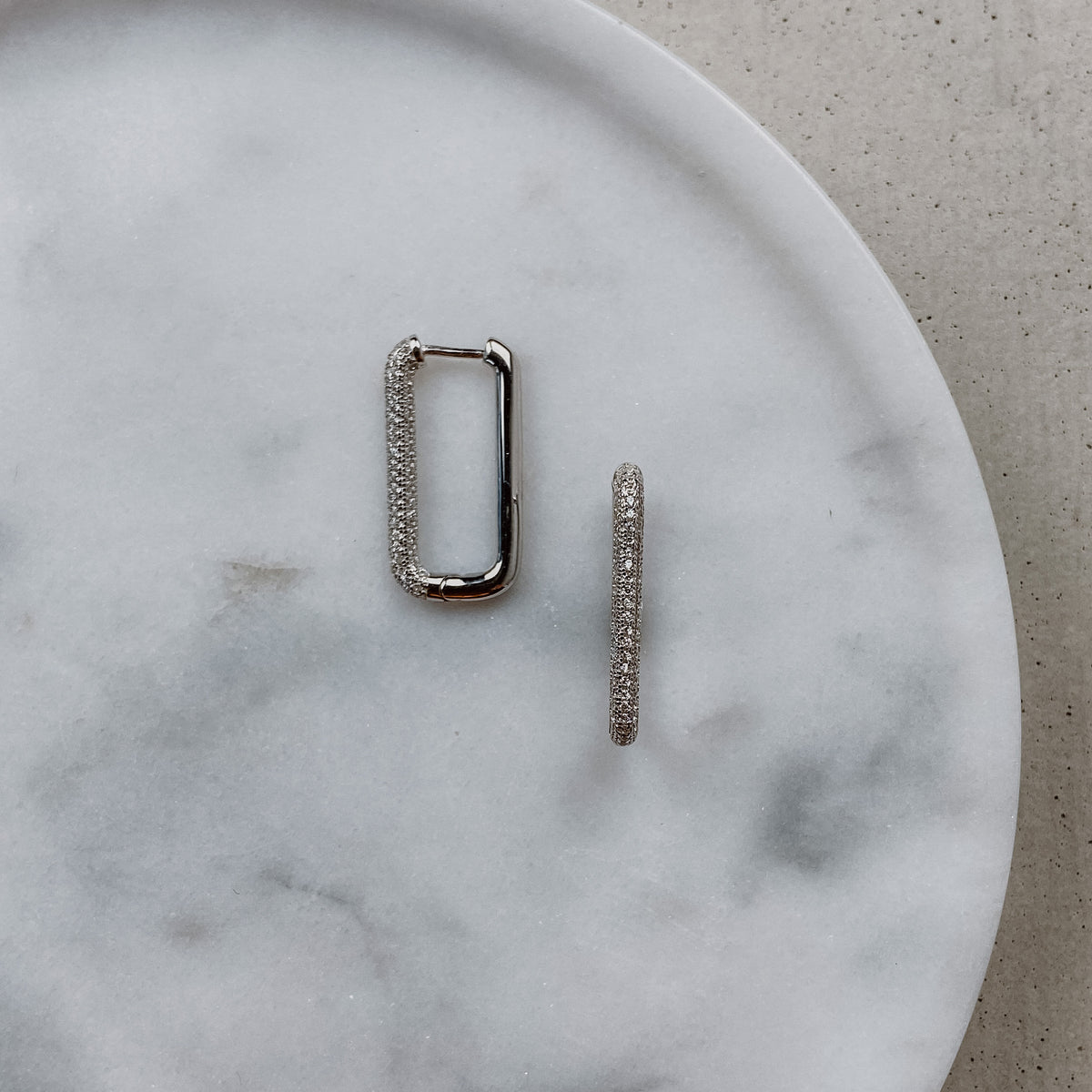 Braut Ohrringe Frederike - Creolen aus 925 Sterlingsilber mit Zirkonia Kristallen, liegend auf einer Marmorplatte