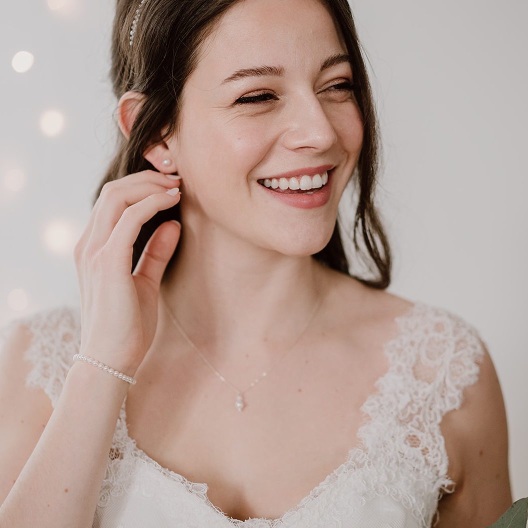 Braut Ohrstecker Perla aus 925 Sterlingsilber mit runder weißer 8mm Perle mit passendem Braut Armband Perla und Braut Halskette Ari, getragen von einem Model