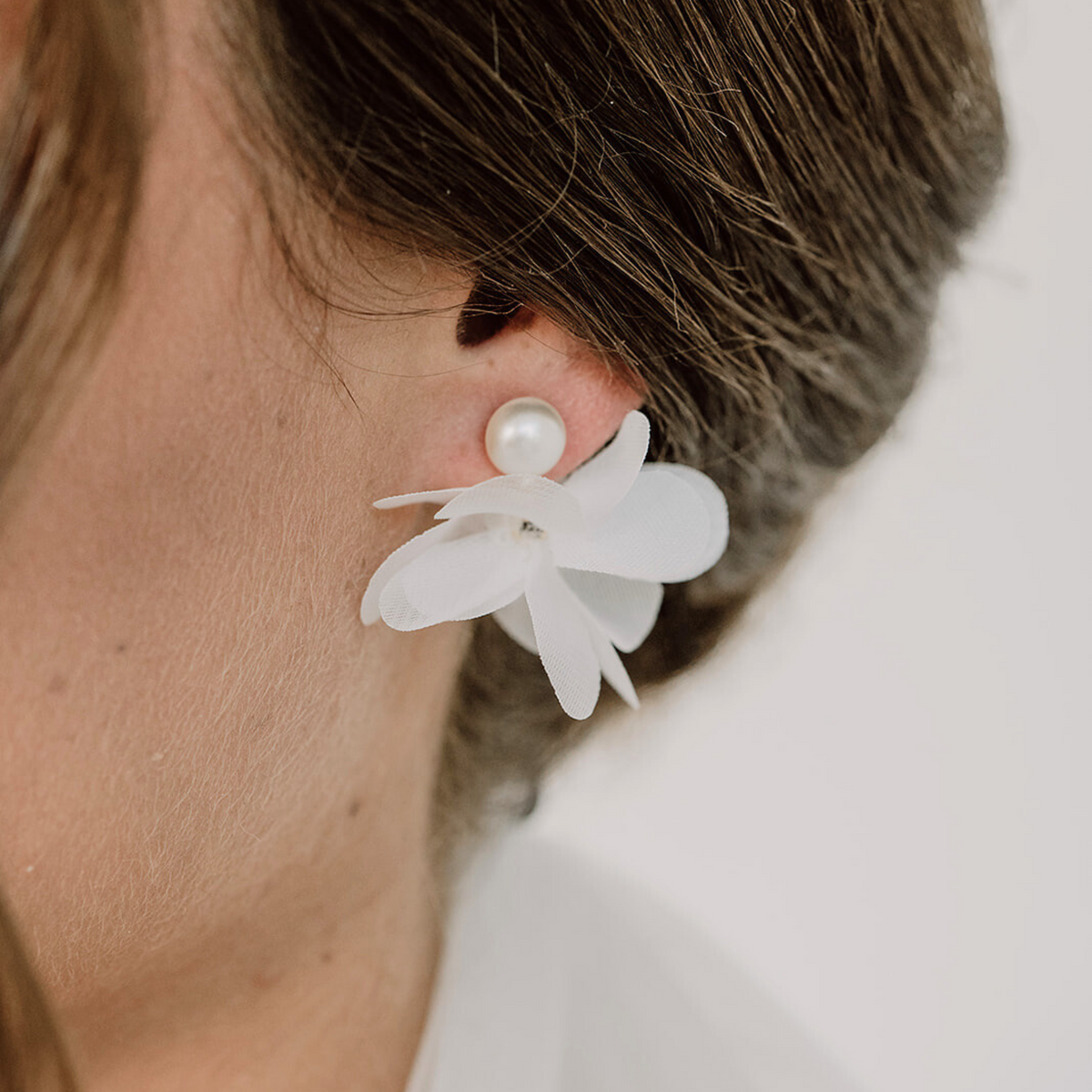 Brautohrringe Emmi mit weißer Stoffblüte aus 925 Sterlingsilber 18K vergoldet, am Model getragen in Nahaufnahme