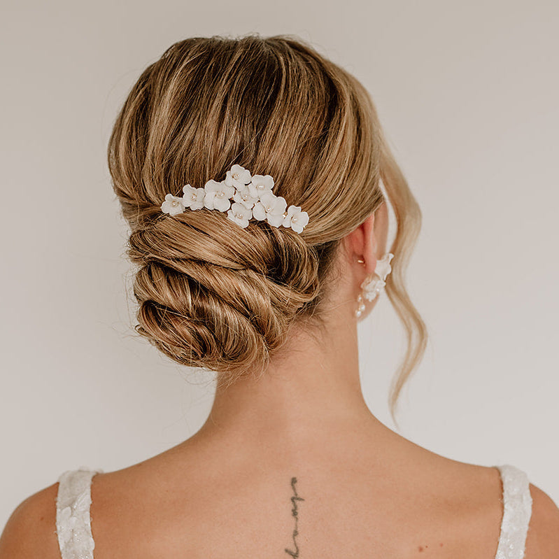 Braut Haarclip Coco in Gold mit weißen Porzellan Blüten und Süßwasserperlen, am Model getragen