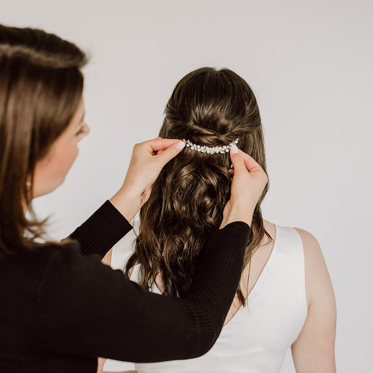 Braut Stylistin steckt Haarkamm Kylie in die Brautfrisur des Models