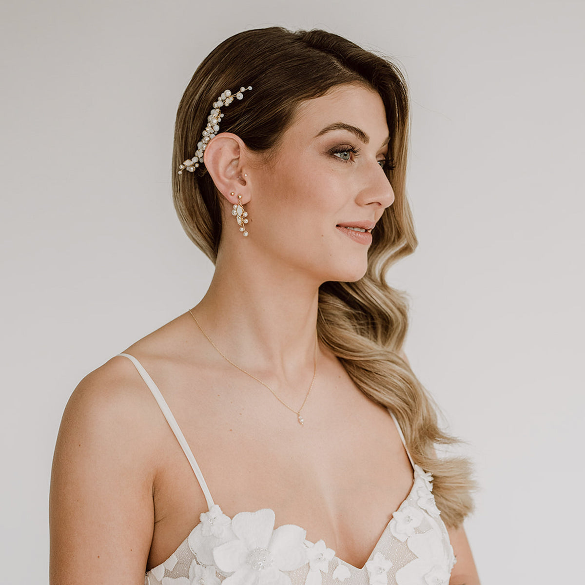 Braut Haarkamm Kylie in Gold mit veganen Perlen, Kristallperlen und white opal Kristallen mit passenden Ohrringen Ana und Halskette Ari, getragen von einem Model in einer halboffenen Brautfrisur