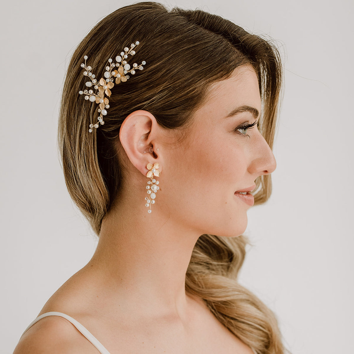 3er Set Braut Haarnadeln Babsi in Gold mit floralen Blüten, Kristallperlen und veganen Perlen mit passenden Braut Ohrringen Babsi, getragen in einer eleganten, halboffenen Brautfrisur