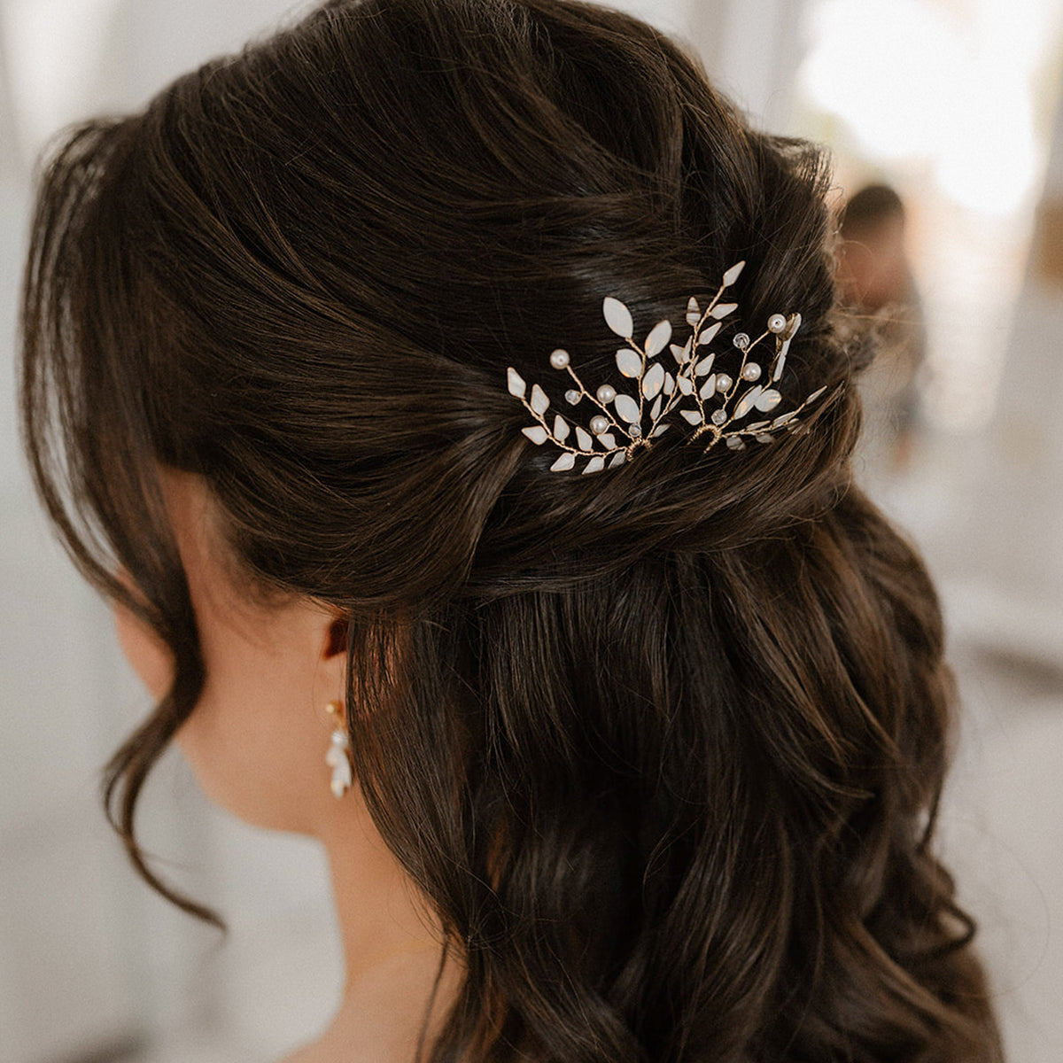 Braut Haarnadeln Gretchen in Gold mit ivoryfarbenen Blättern, white opal Kristallen in Blattform, veganen Perlen und Kristallperlen, zu sehen in einer Brautfrisur mit halb offenem Haar in Nahaufnahme